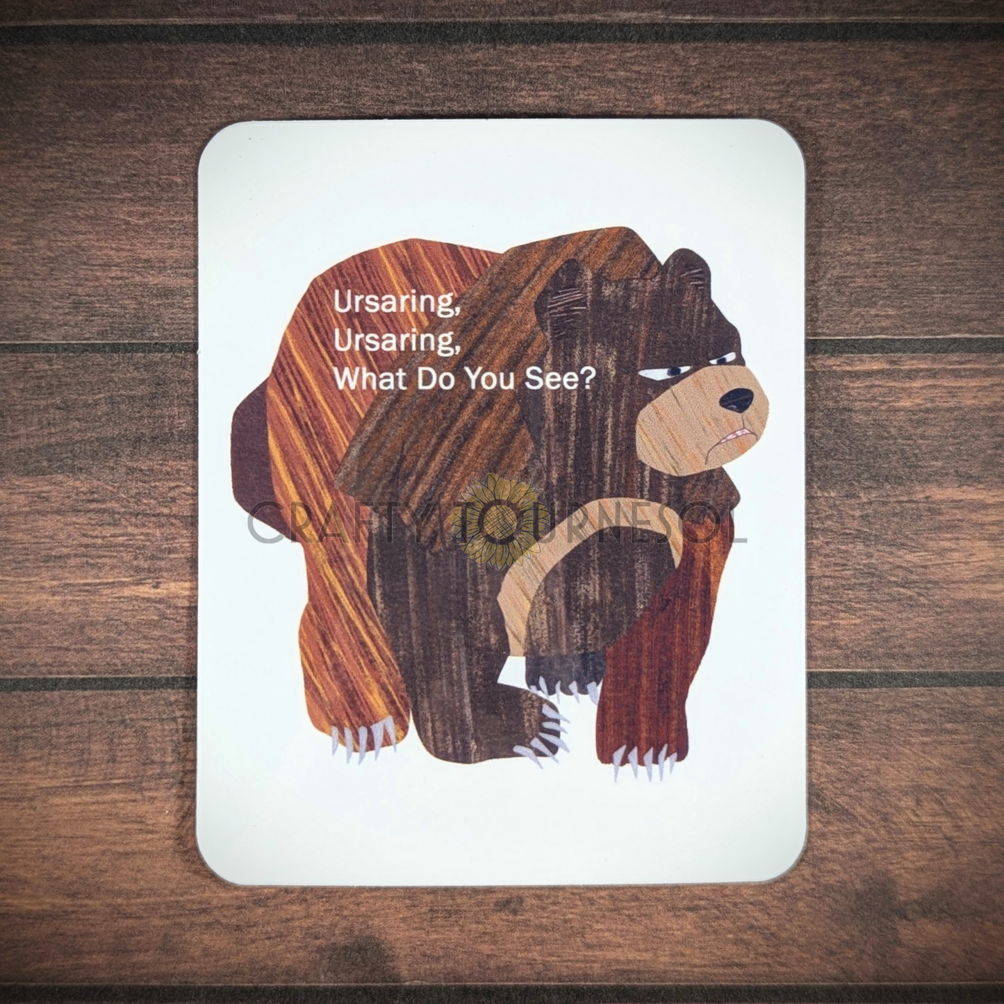 "Vinyl sticker titled 'Ursaring, Ursaring, What Do You See?," featuring a brown Ursaring on all fours, styled like the children's book character Brown Bear, Brown Bear, blending storybook charm and gaming aesthetics, set against a dark wooden and blurred background."