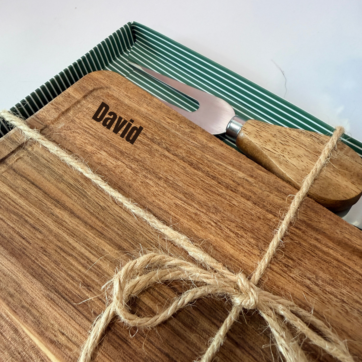 Personalized mini acacia wood charcuterie board with custom laser engraving, approximately 9.5 x 4.7 inches. Includes two serving tools, standard or cursive font options, and gift wrapping for a ready-to-give present.

