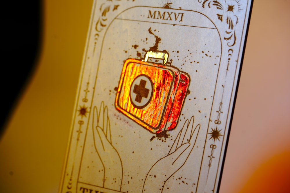 Laser-engraved wooden tarot card inspired by Dead by Daylight, featuring "The Survivor" medkit design, with red foiled accents. Horror game decor, perfect for DBD fans and collectors.