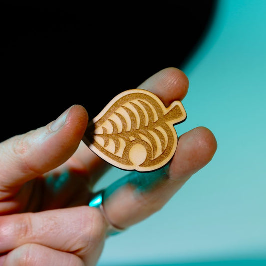 Laser engraved wood pin shaped like the Animal Crossing leaf, perfect gamer gift or accessory for backpacks, jackets, or collectors of gaming-themed items.