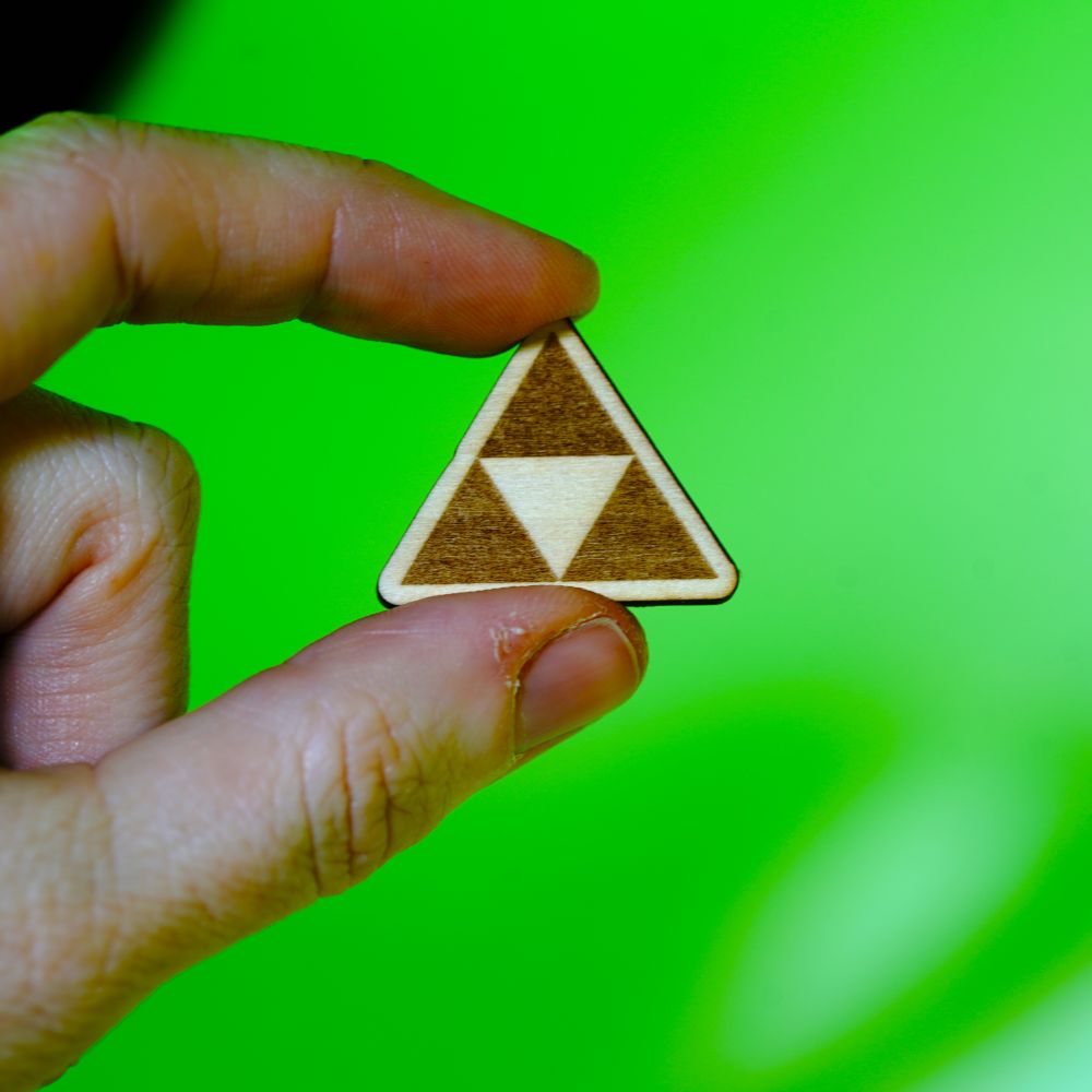 Laser engraved wood pin featuring the iconic Triforce symbol from Zelda. A handmade accessory perfect for gamers, fantasy lovers, and geeky gift collectors.