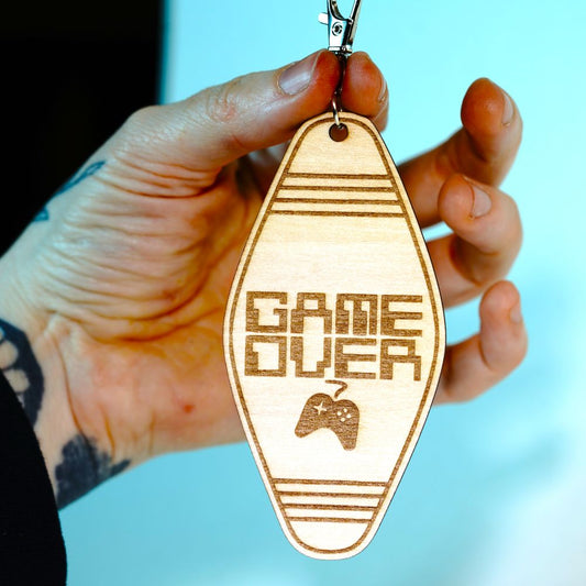 Laser engraved wood motel-style keychain featuring the phrase “Game Over” with a retro controller design. Perfect funny gift for gamers and nostalgia lovers.