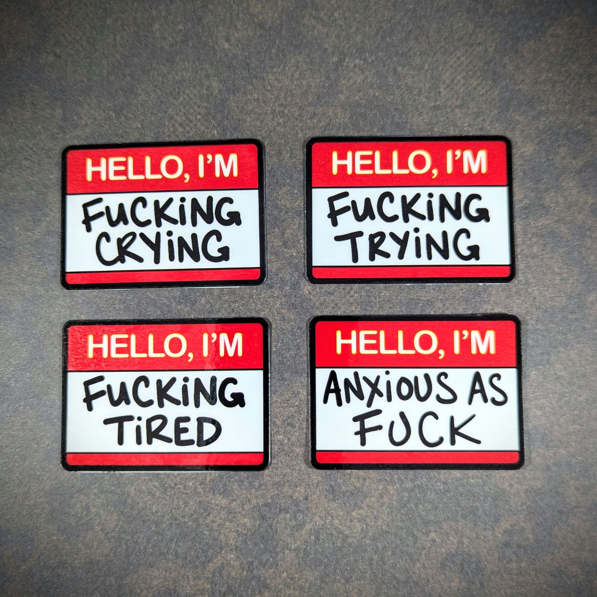 "Set of humorous 'Hello, I'm' stickers with phrases like 'f***ing crying,' 'f***ing trying,' 'f***ing tired,' and 'anxious as f***.' Perfect for expressing moods with edgy, relatable humor."