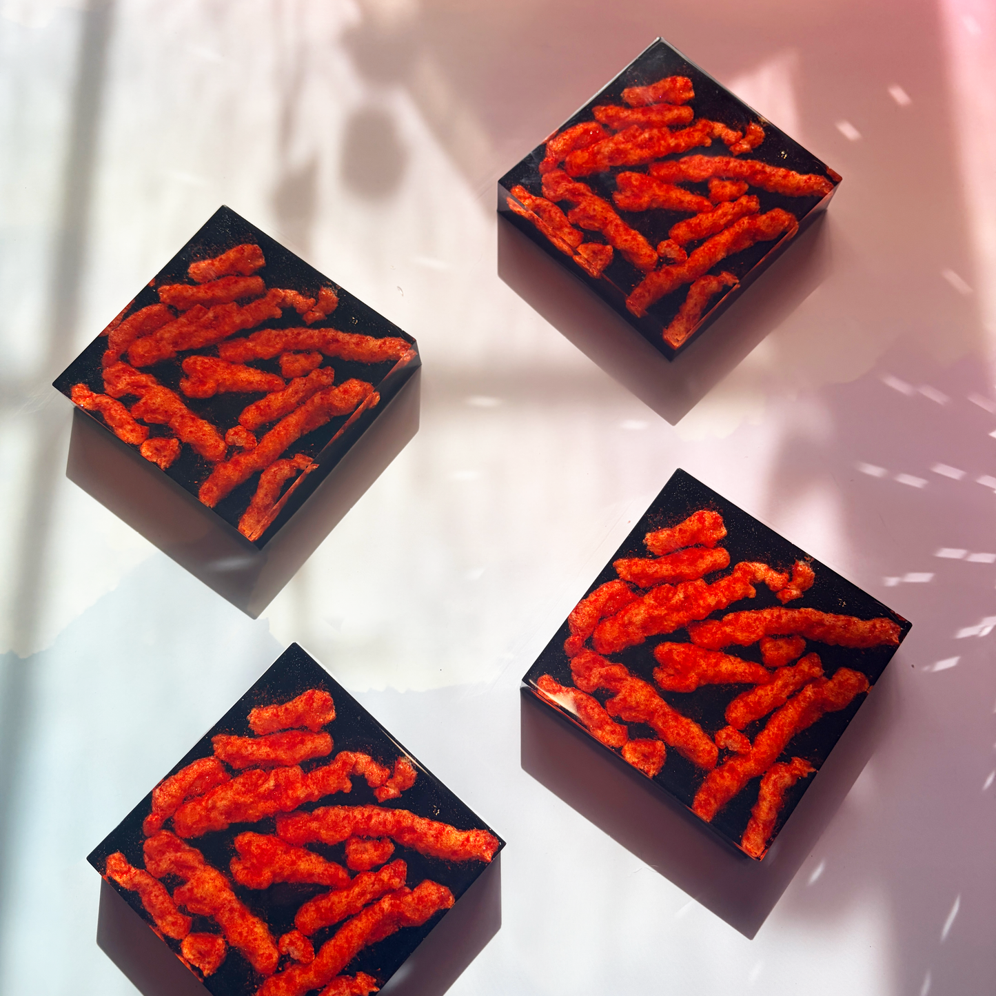 Resin coaster inlaid with Hot Cheetos and black backing.