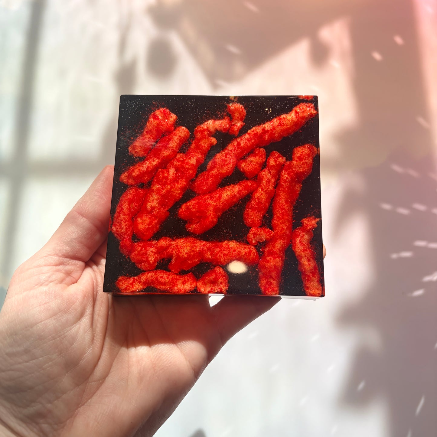 Resin coaster inlaid with Hot Cheetos and black backing.