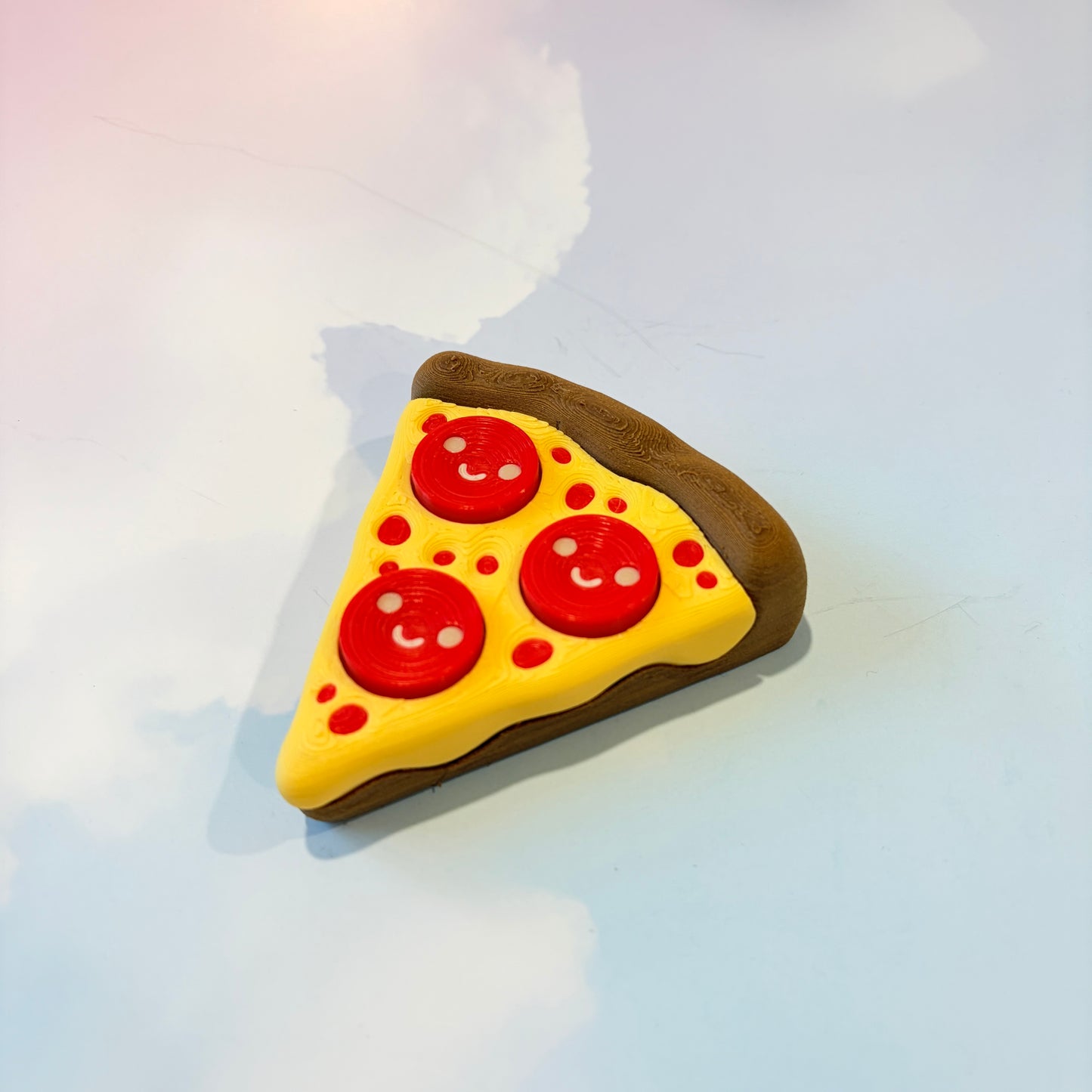 Pizza slice fidget clicker with smiley pepperoni toppings.
