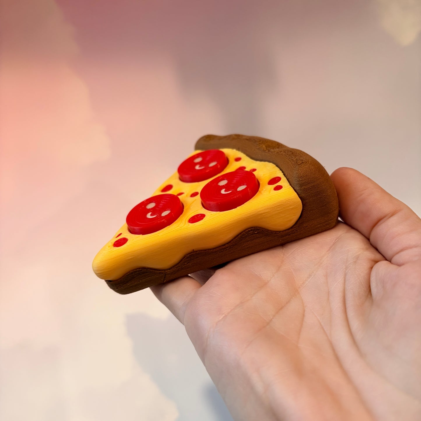 Pizza slice fidget clicker with smiley pepperoni toppings.