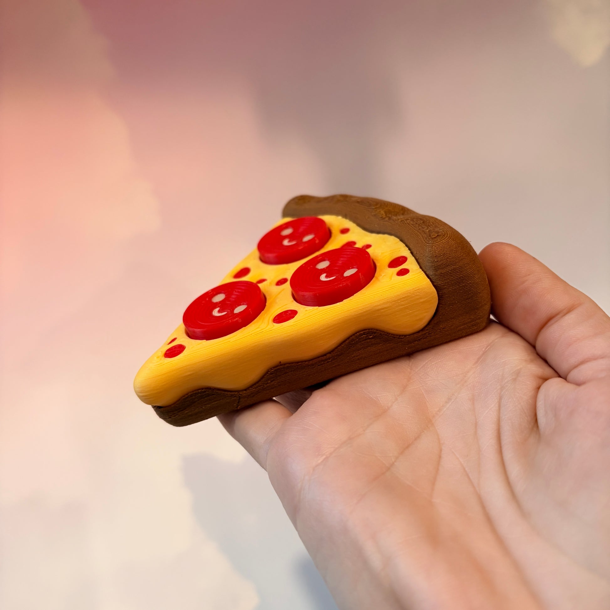 Pizza slice fidget clicker with smiley pepperoni toppings.