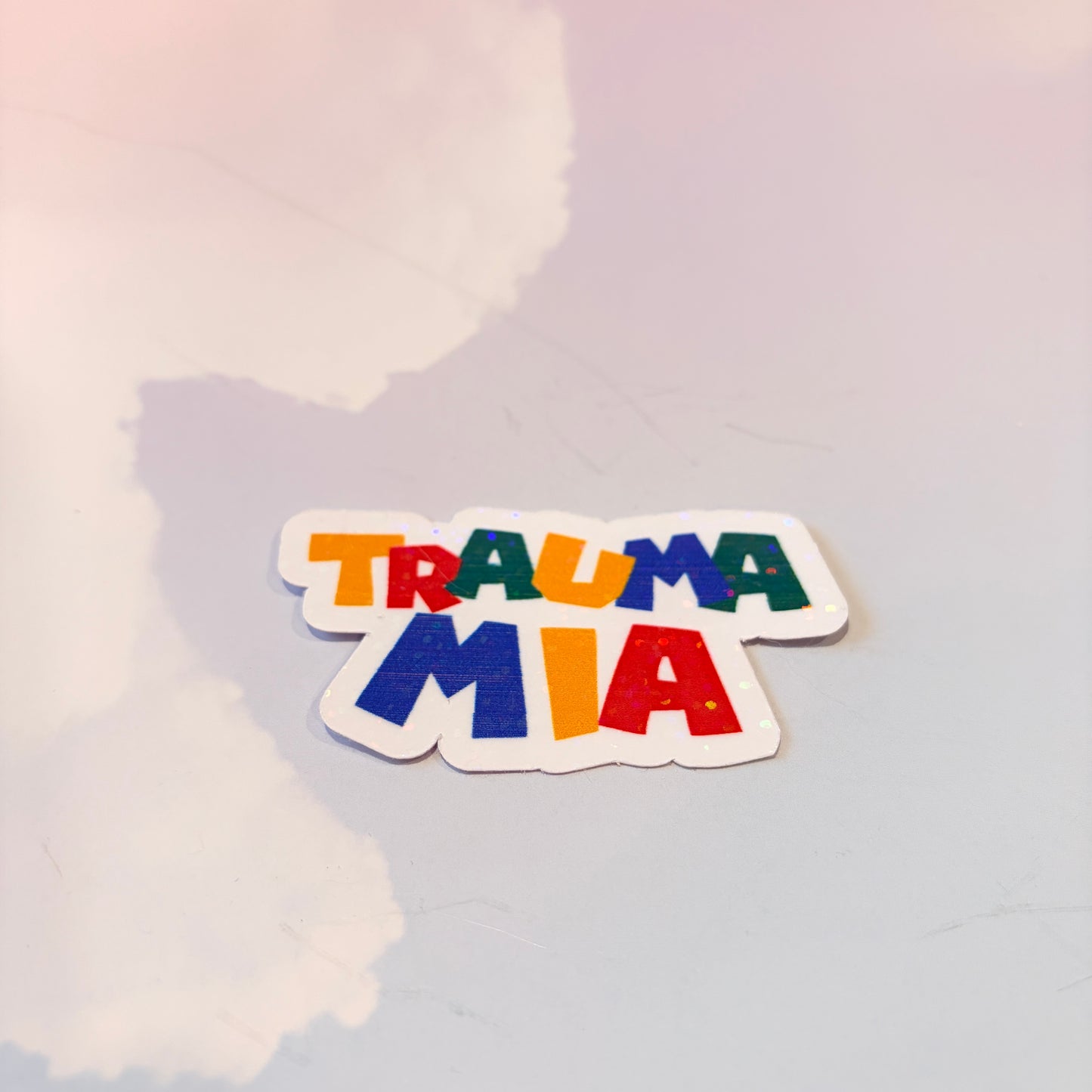 Holographic Trauma Mia sticker in retro video game style lettering.