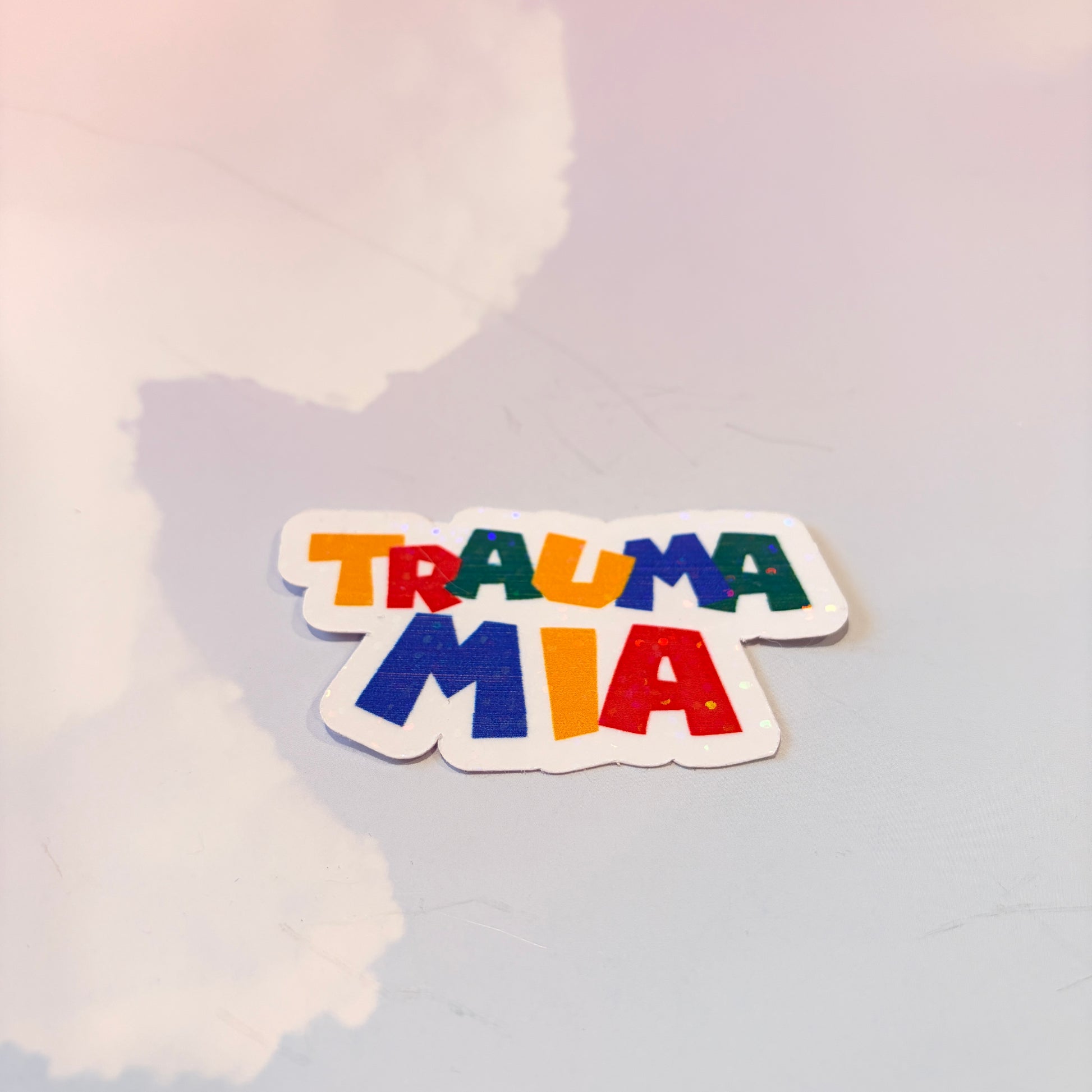 Holographic Trauma Mia sticker in retro video game style lettering.