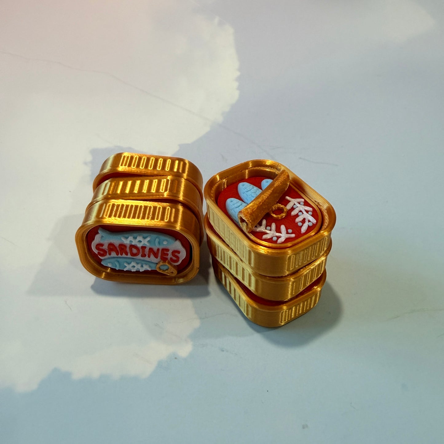 Sardine tin fidget clicker inspired by tinned fish packaging.