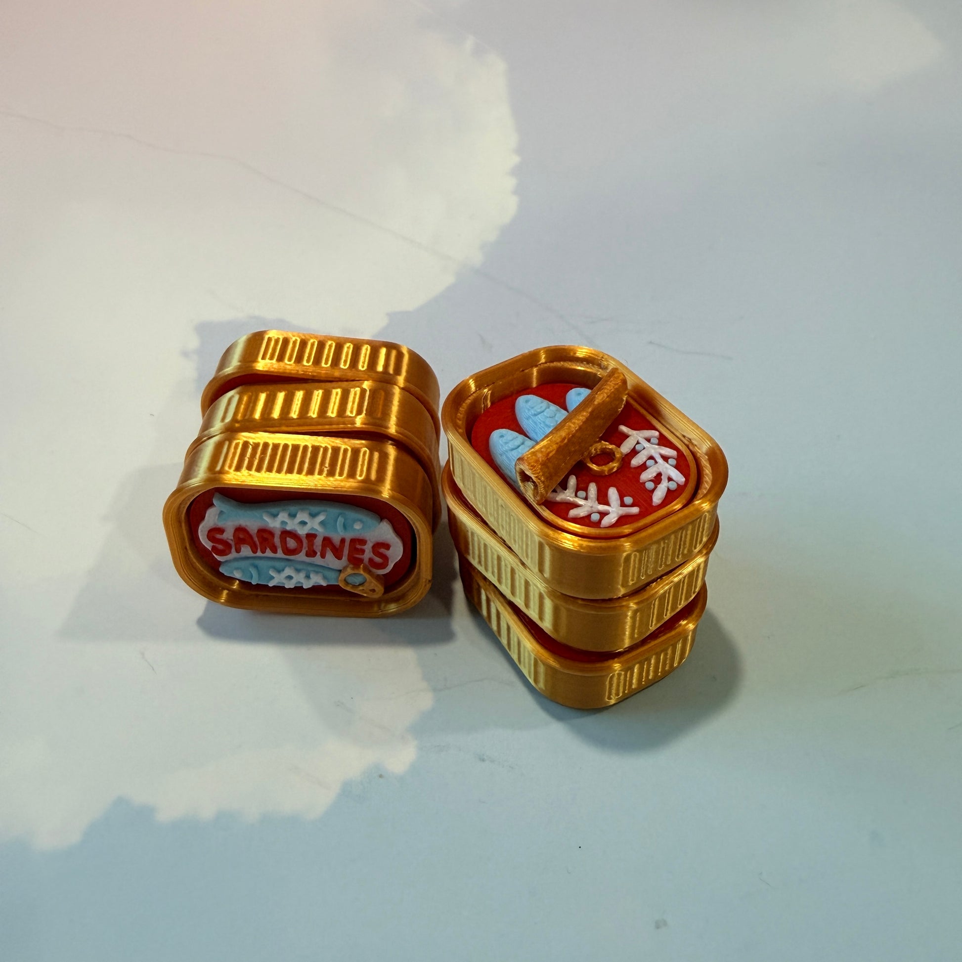 Sardine tin fidget clicker inspired by tinned fish packaging.