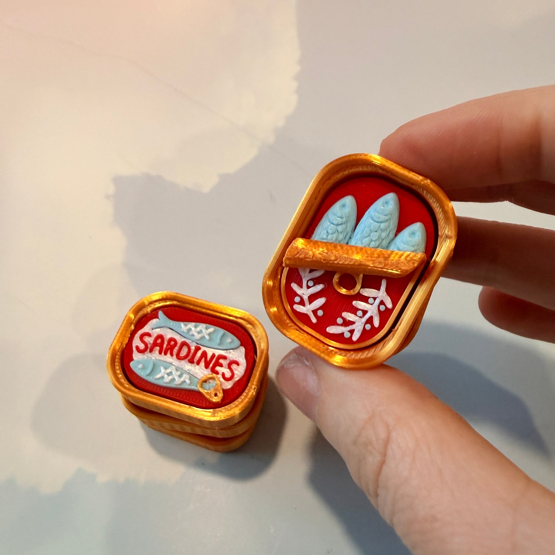Sardine tin fidget clicker inspired by tinned fish packaging.