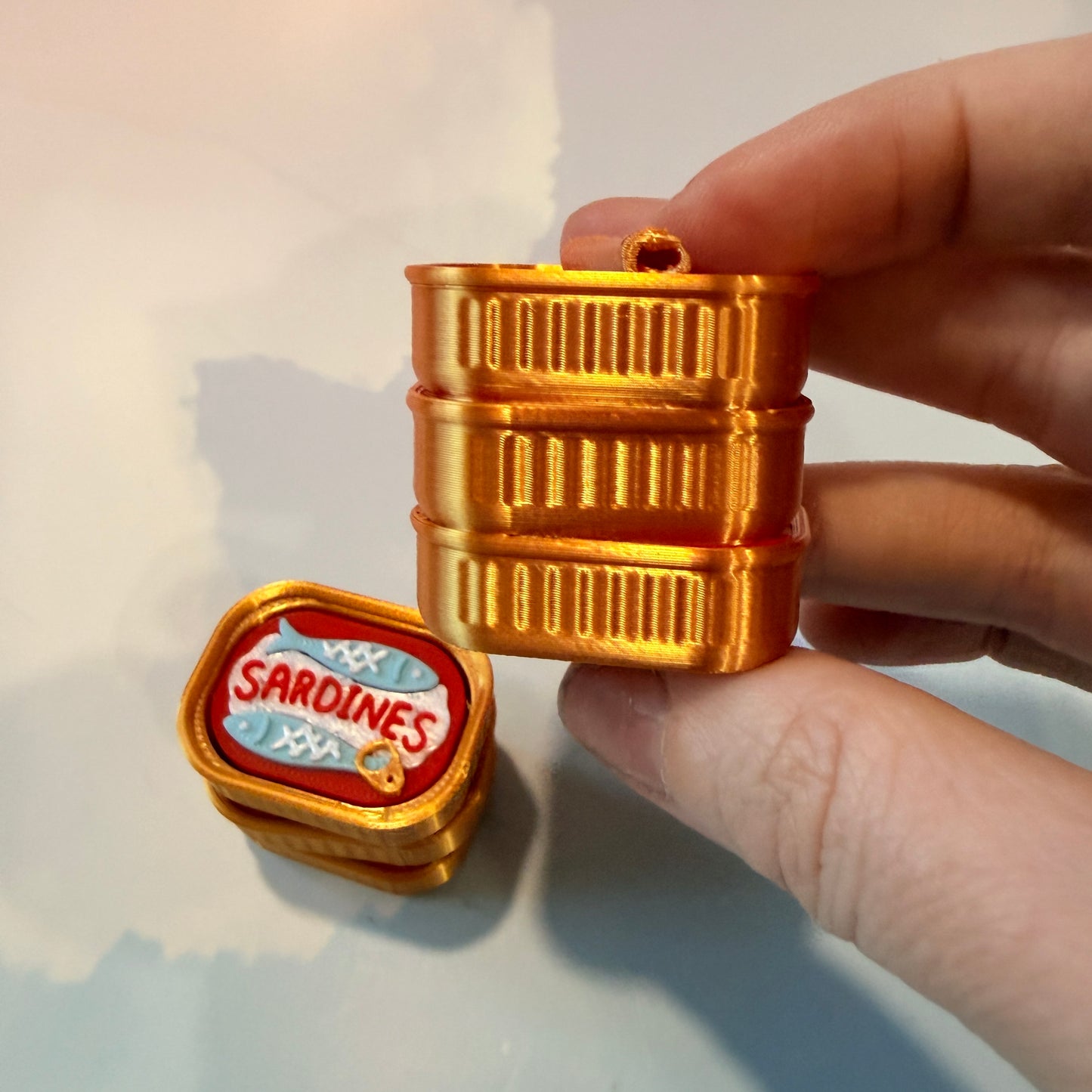 Sardine tin fidget clicker inspired by tinned fish packaging.
