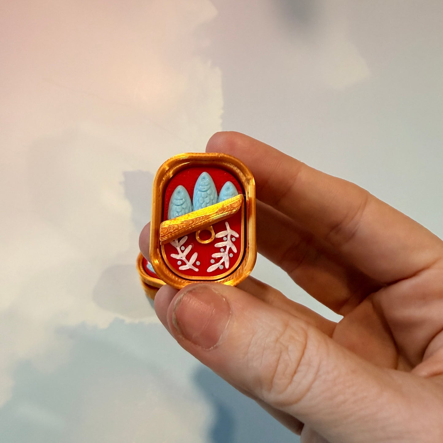 Sardine tin fidget clicker inspired by tinned fish packaging.