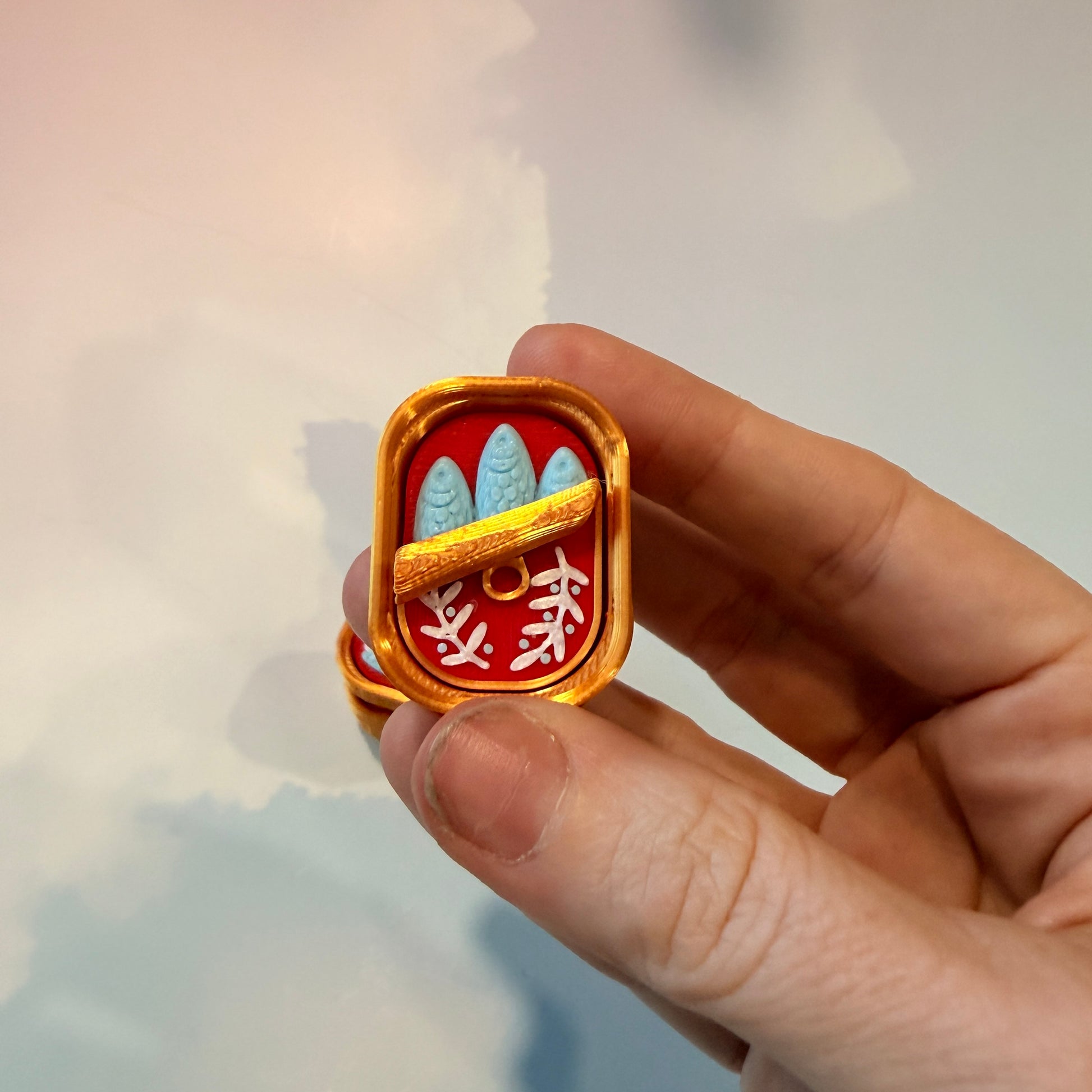 Sardine tin fidget clicker inspired by tinned fish packaging.