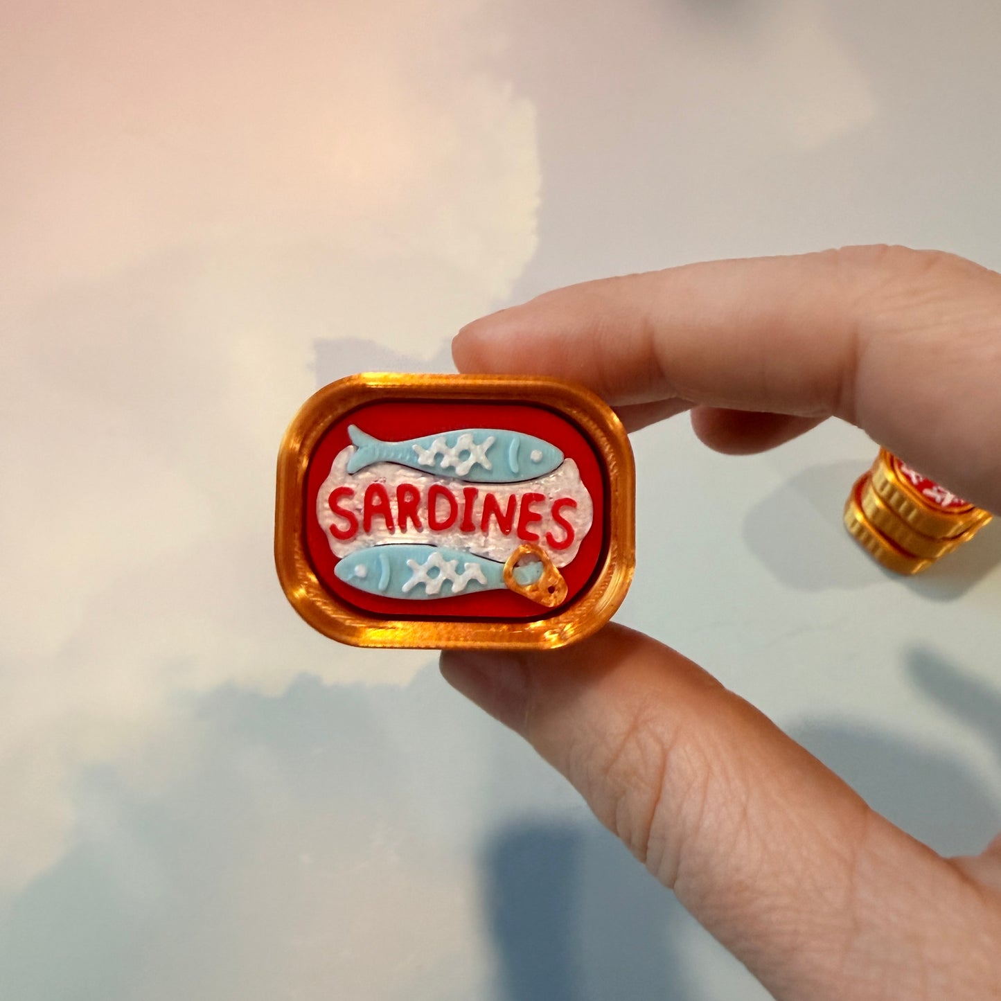 Sardine tin fidget clicker inspired by tinned fish packaging.