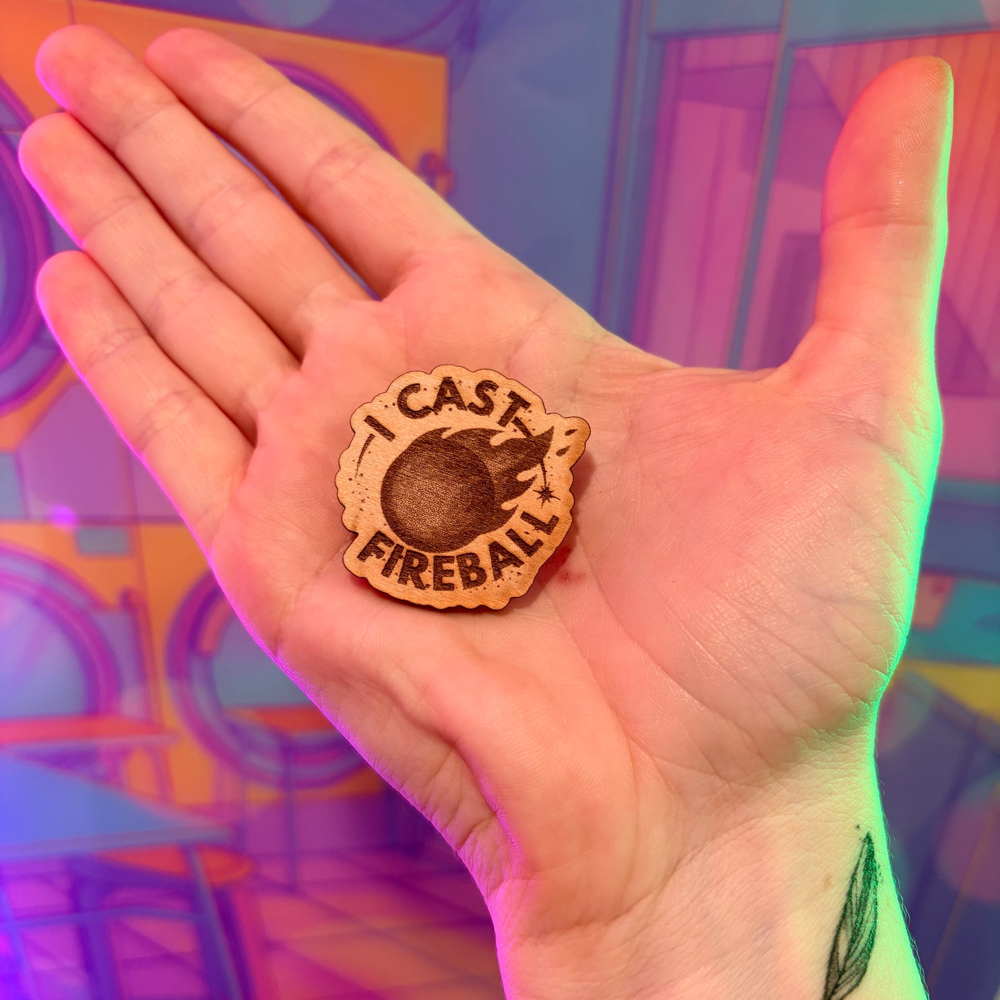 Laser engraved basswood pin reading "I Cast Fireball" for tabletop gamers.