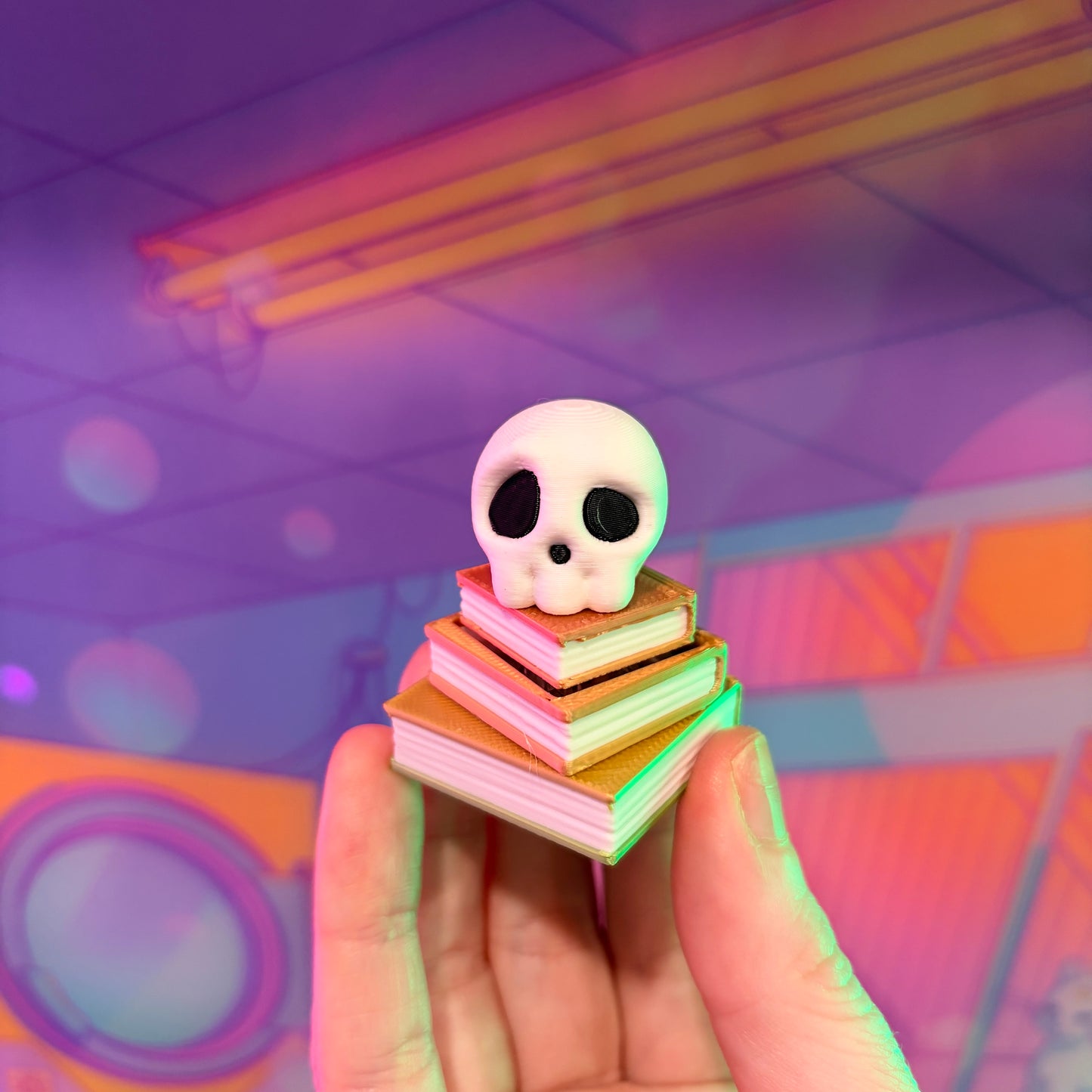 3D printed skull fidget clicker on an ombre stack of books.