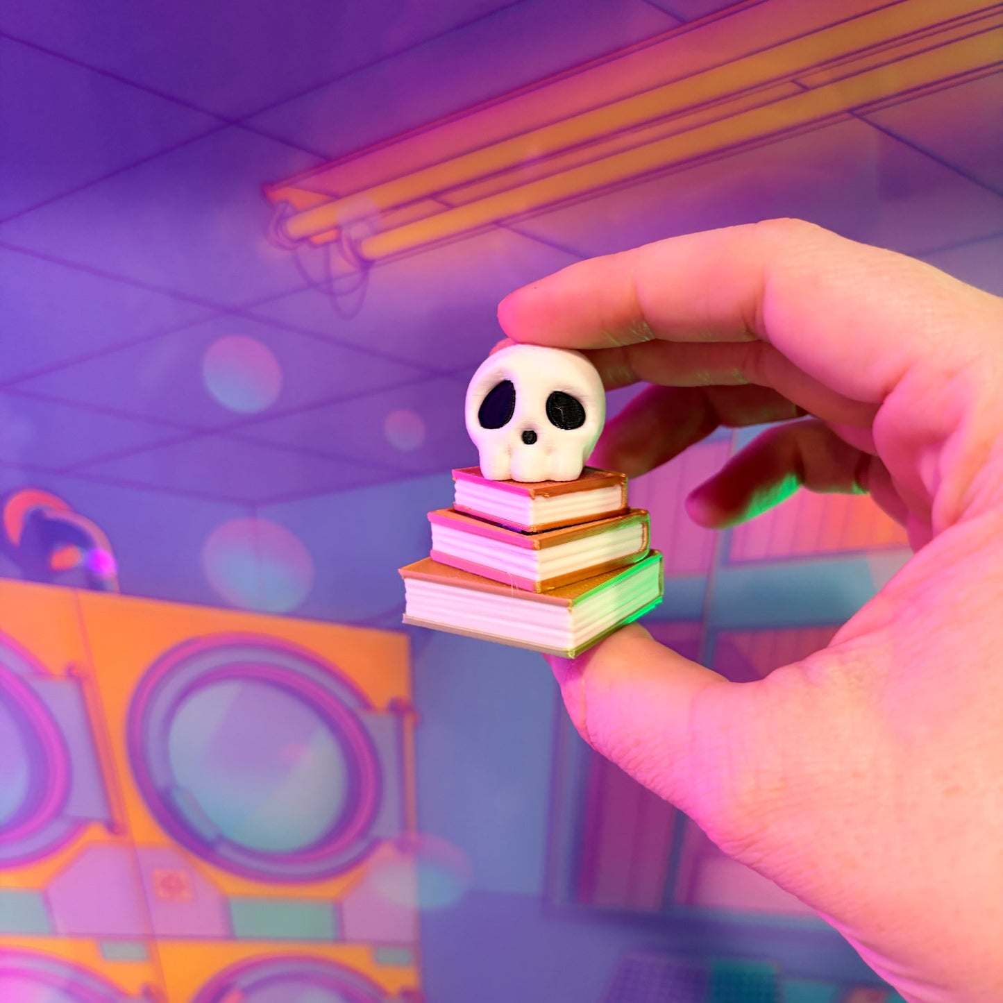 3D printed skull fidget clicker on an ombre stack of books.
