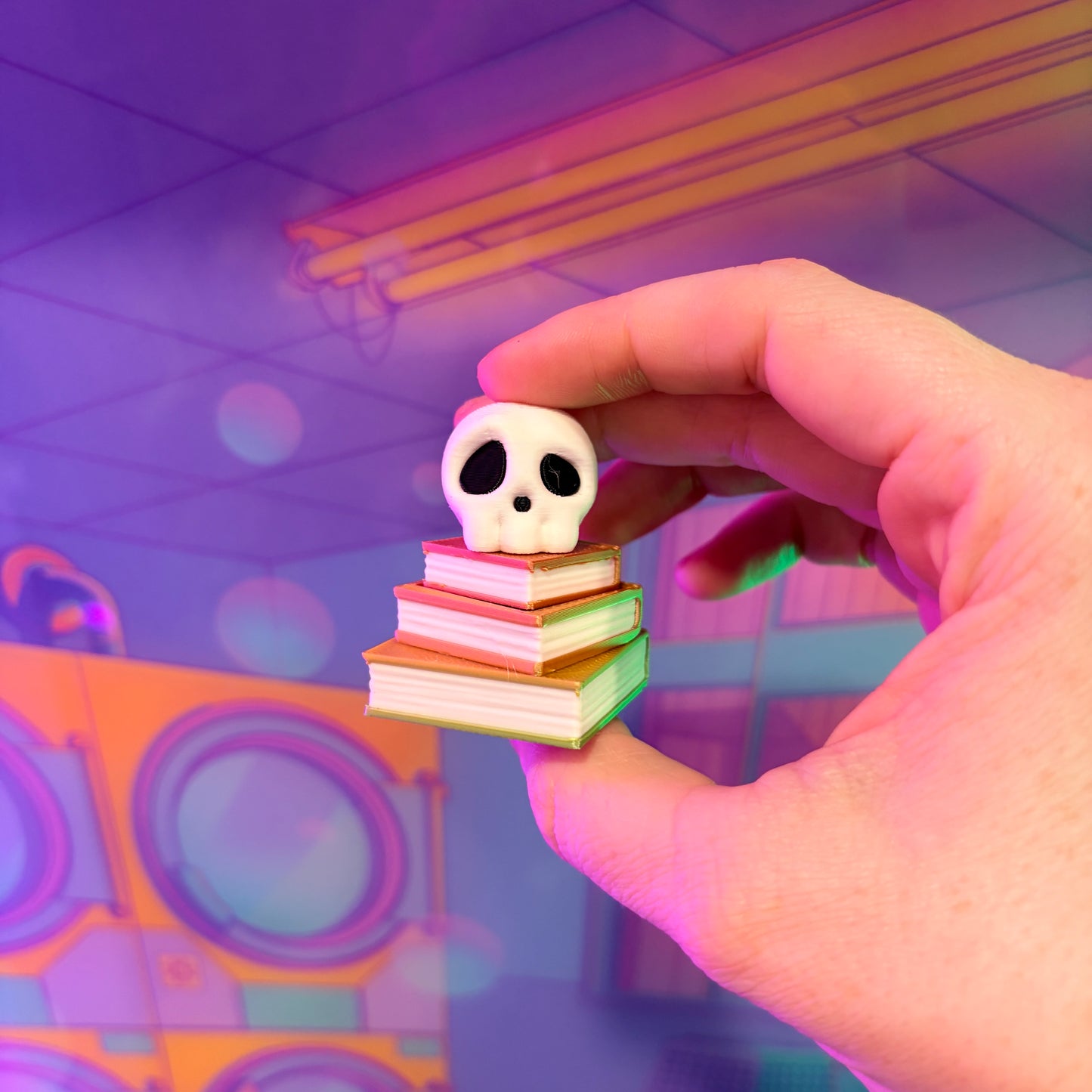 3D printed skull fidget clicker on an ombre stack of books.