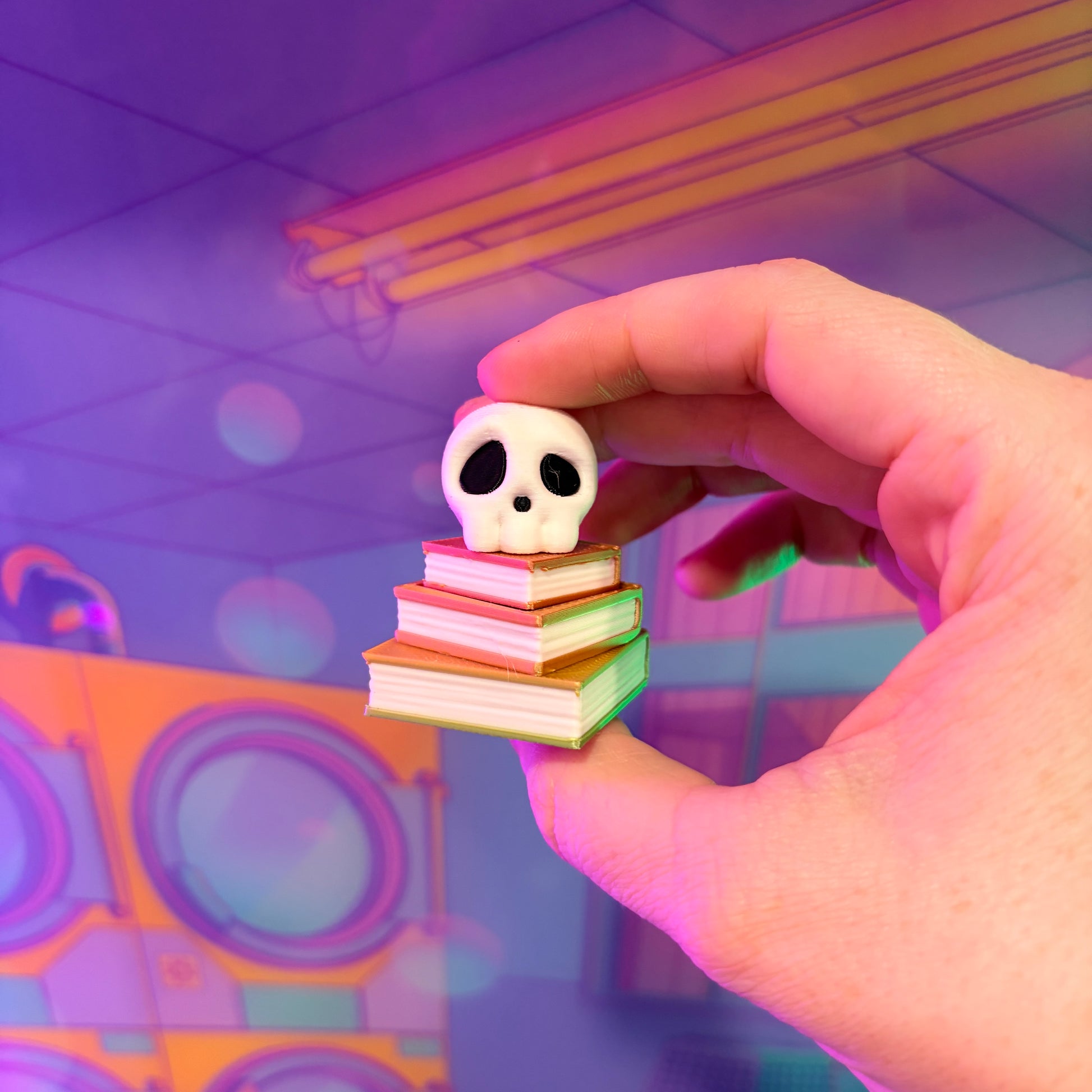 3D printed skull fidget clicker on an ombre stack of books.