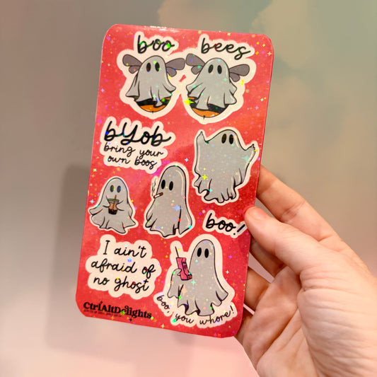 Holographic sticker sheet featuring eight cute ghost vinyl stickers with funny sayings including "Boo Bees," "BYOB Bring Your Own Boos," "I Ain't Afraid of No Ghost," and other snarky spooky designs on a pink glitter background.