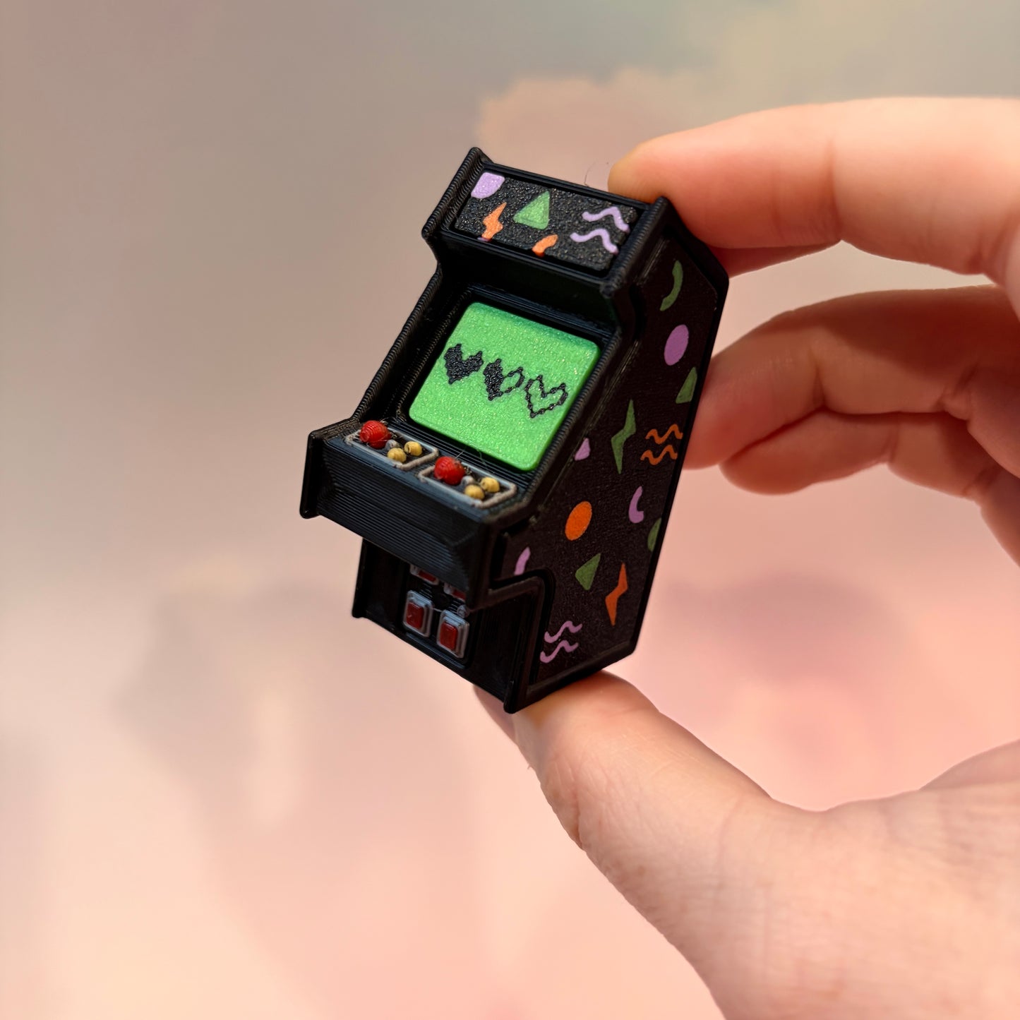 Mini retro arcade machine fidget clicker keychain with colorful 90s-inspired graphics, green screen, and 3D printed design, available in clicky or silent.