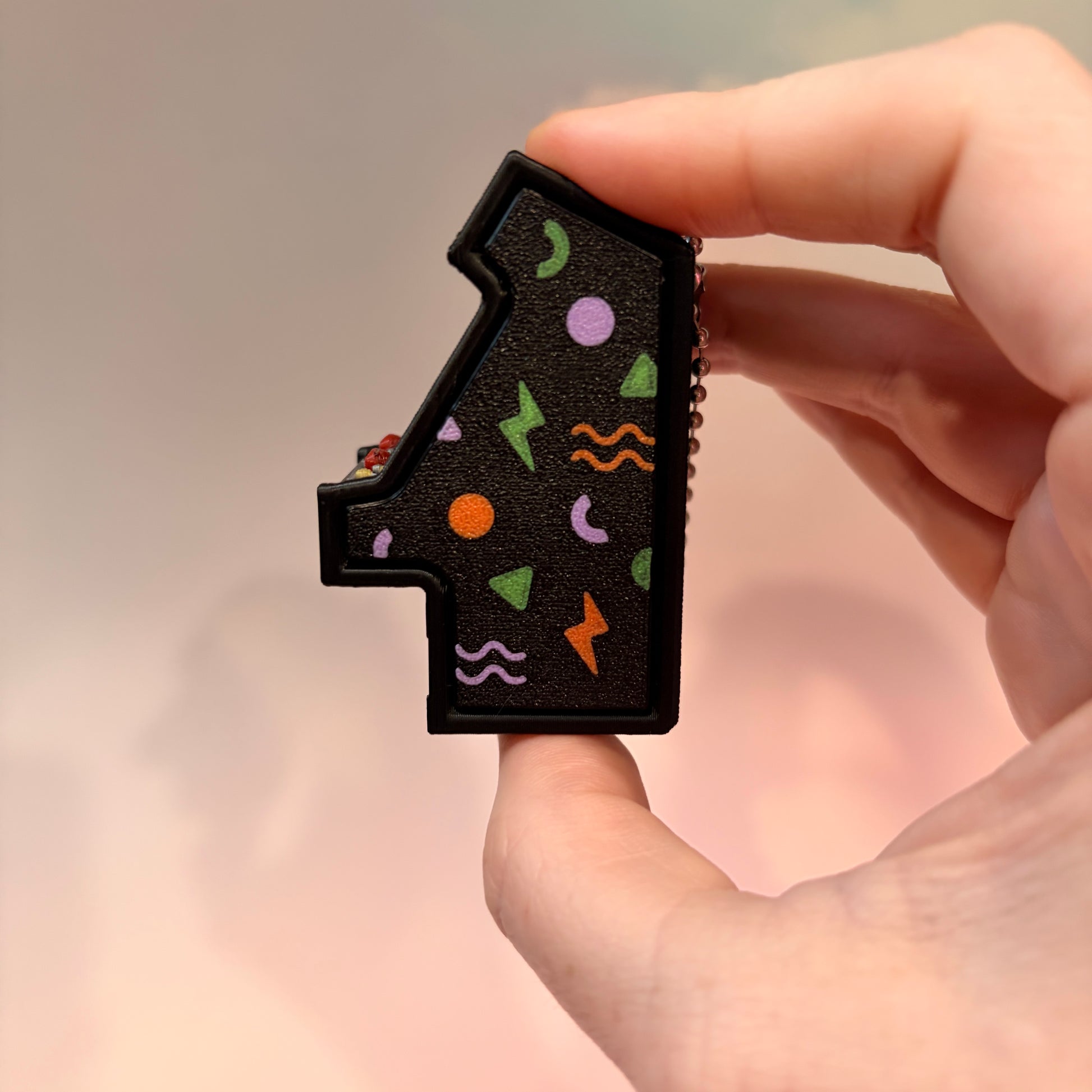Mini retro arcade machine fidget clicker keychain with colorful 90s-inspired graphics, green screen, and 3D printed design, available in clicky or silent.