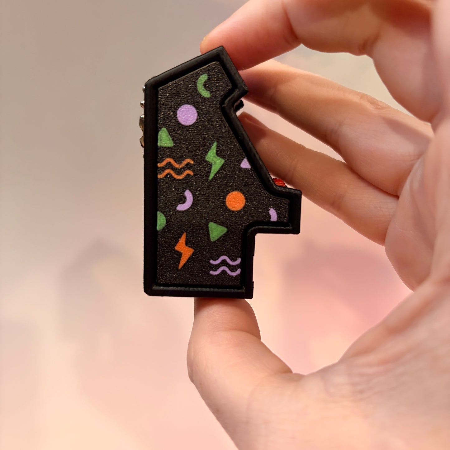 Mini retro arcade machine fidget clicker keychain with colorful 90s-inspired graphics, green screen, and 3D printed design, available in clicky or silent.