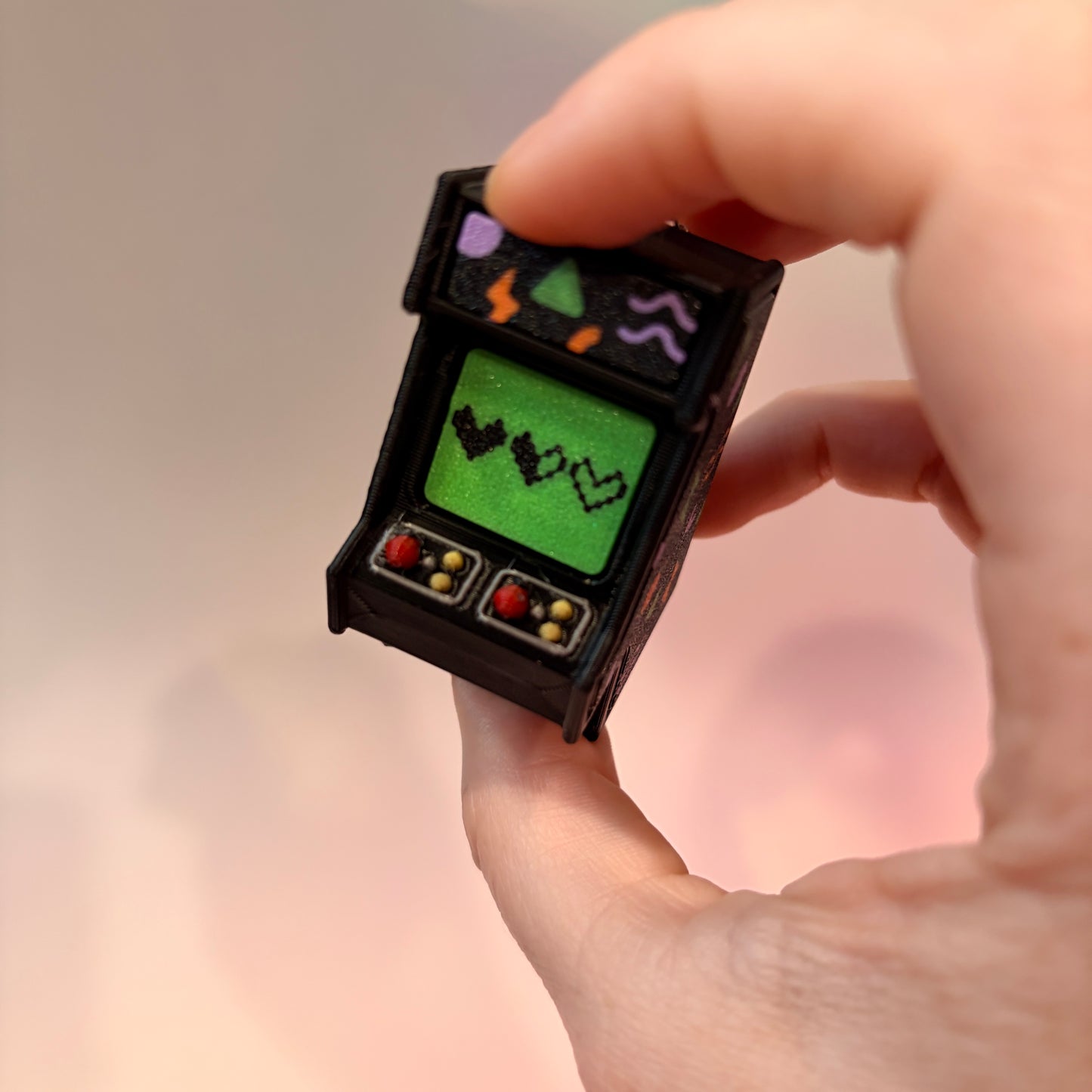 Mini retro arcade machine fidget clicker keychain with colorful 90s-inspired graphics, green screen, and 3D printed design, available in clicky or silent.