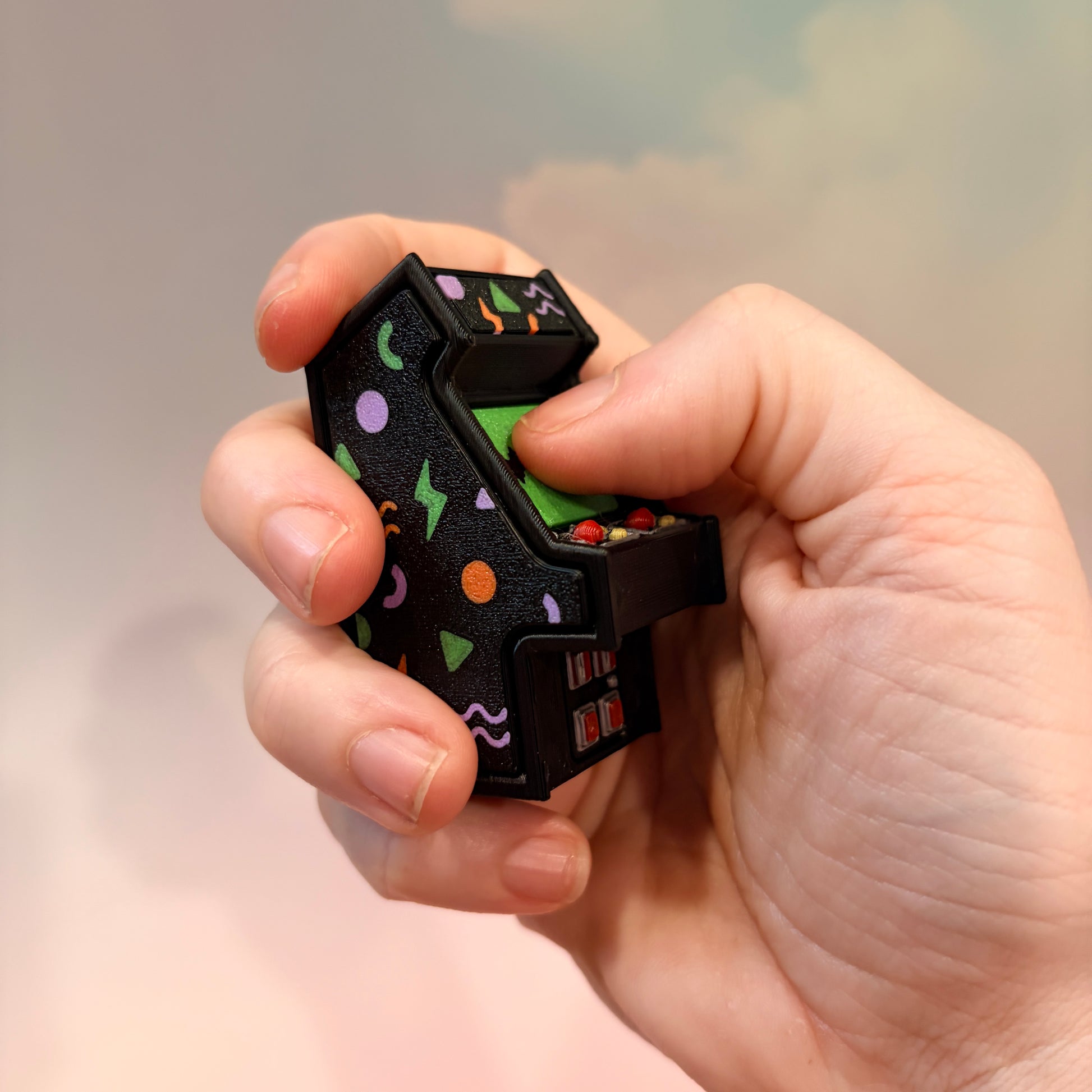 Mini retro arcade machine fidget clicker keychain with colorful 90s-inspired graphics, green screen, and 3D printed design, available in clicky or silent.