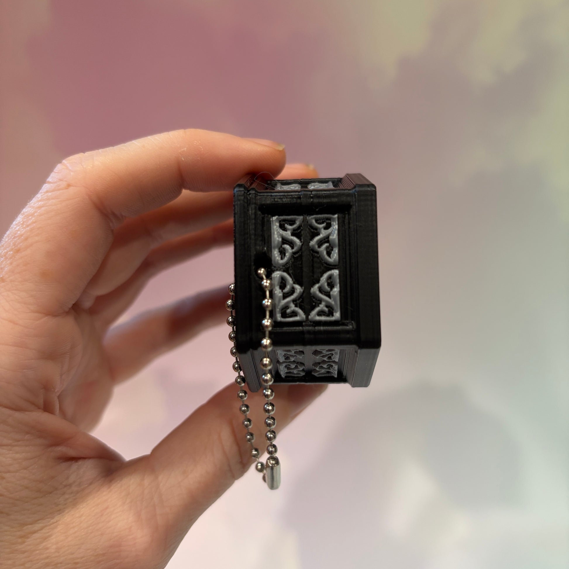 Mini 3D printed black coffin shelf fidget clicker with silver gothic trim and red interior. Features three decorative keycaps: a framed black spider, a ghost reading a book, and a bubbling green cauldron. Includes a silver keychain and is available with clicky or silent switches.