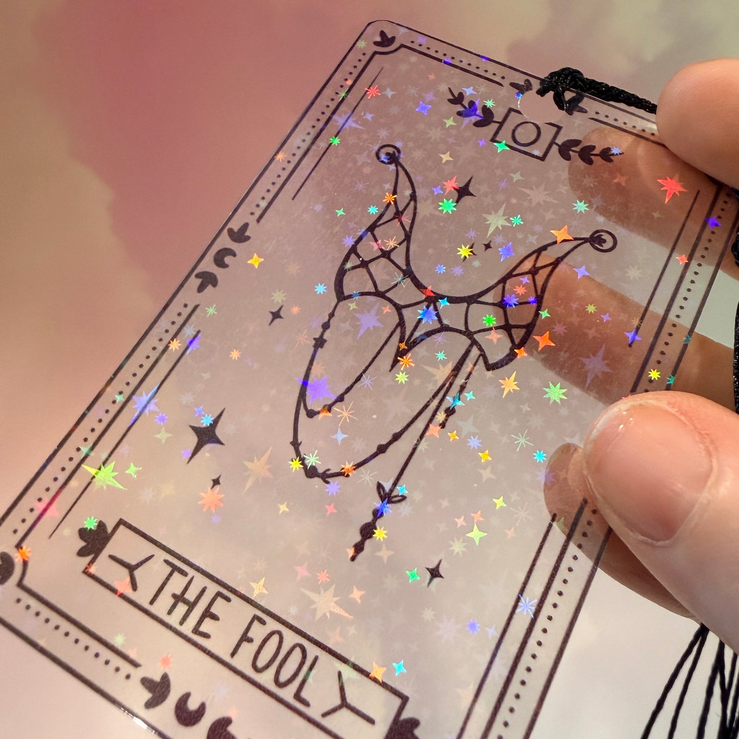Clear holographic tarot card bookmark with elegant black line art on transparent waterproof cardstock. Finished with a black tassel and shimmering holographic pattern that changes in the light. Available in all 22 Major Arcana designs.
