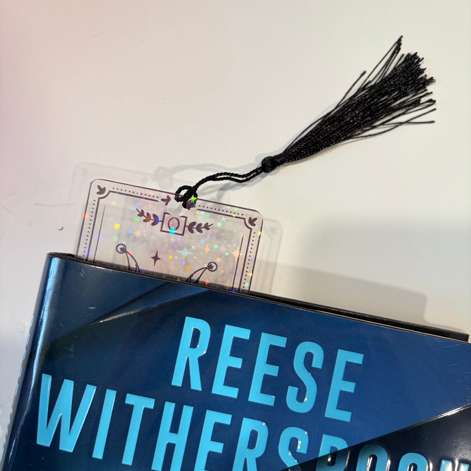 Clear holographic tarot card bookmark with elegant black line art on transparent waterproof cardstock. Finished with a black tassel and shimmering holographic pattern that changes in the light. Available in all 22 Major Arcana designs.