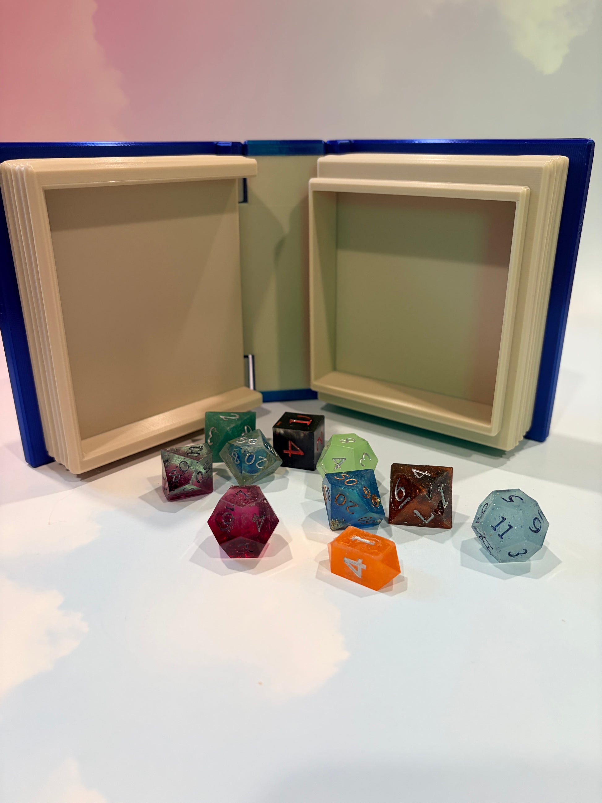 Royal blue and metallic gold 3D printed book box with a celestial moon and stars design on the cover. Opens to reveal a hidden storage compartment that holds 1–2 sets of RPG dice and doubles as a rolling tray. Perfect for jewelry, trinkets, and tabletop gaming accessories.