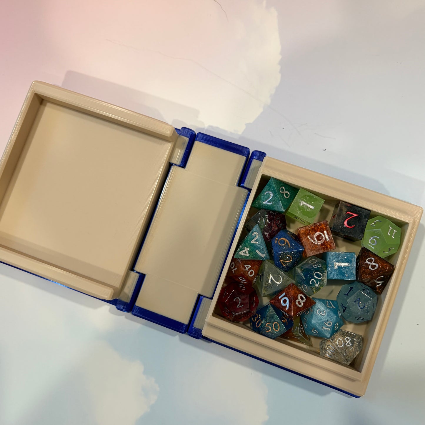 Royal blue and metallic gold 3D printed book box with a celestial moon and stars design on the cover. Opens to reveal a hidden storage compartment that holds 1–2 sets of RPG dice and doubles as a rolling tray. Perfect for jewelry, trinkets, and tabletop gaming accessories.