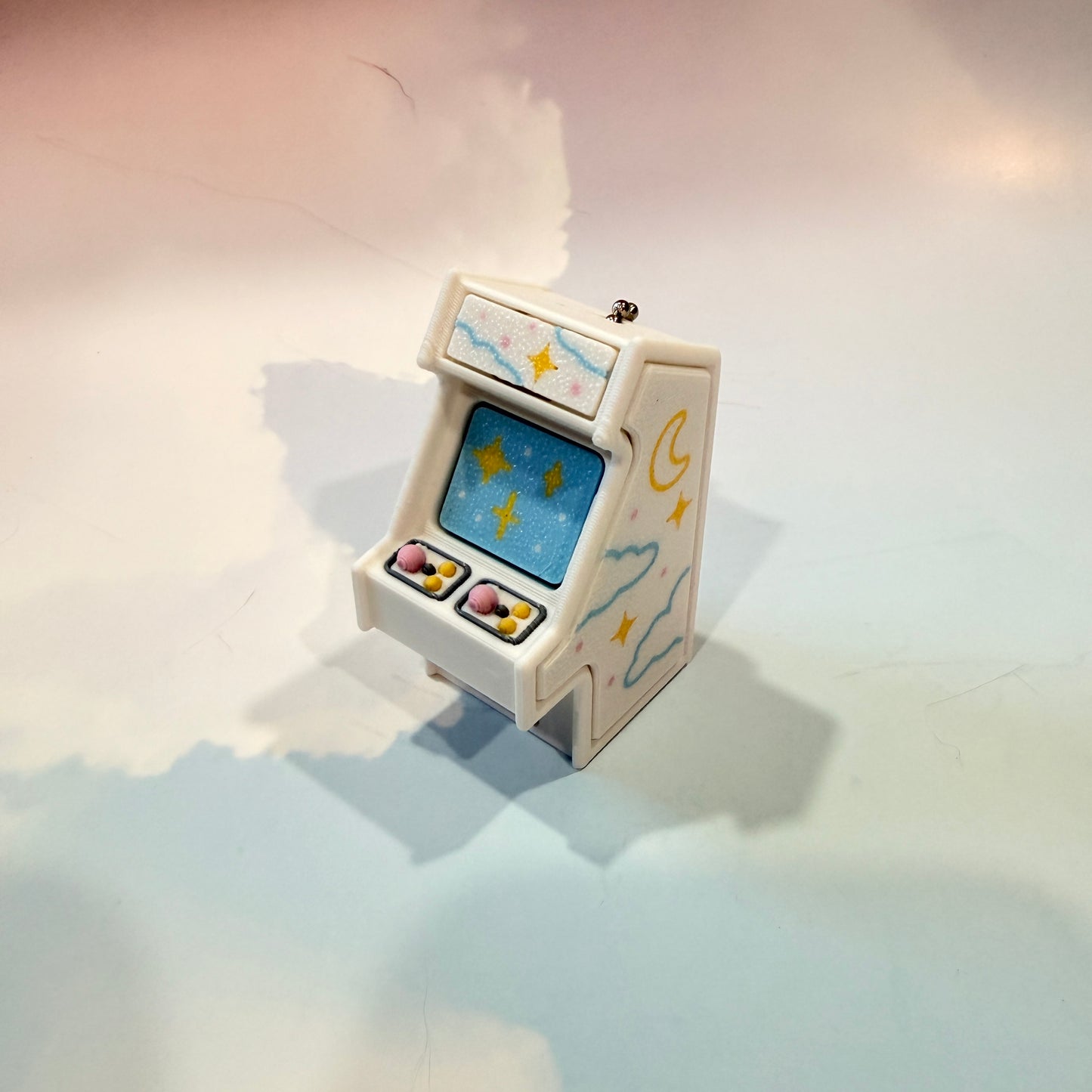 Mini retro arcade machine fidget clicker keychain with pastel color way, blue screen, and 3D printed design, available in clicky or silent.