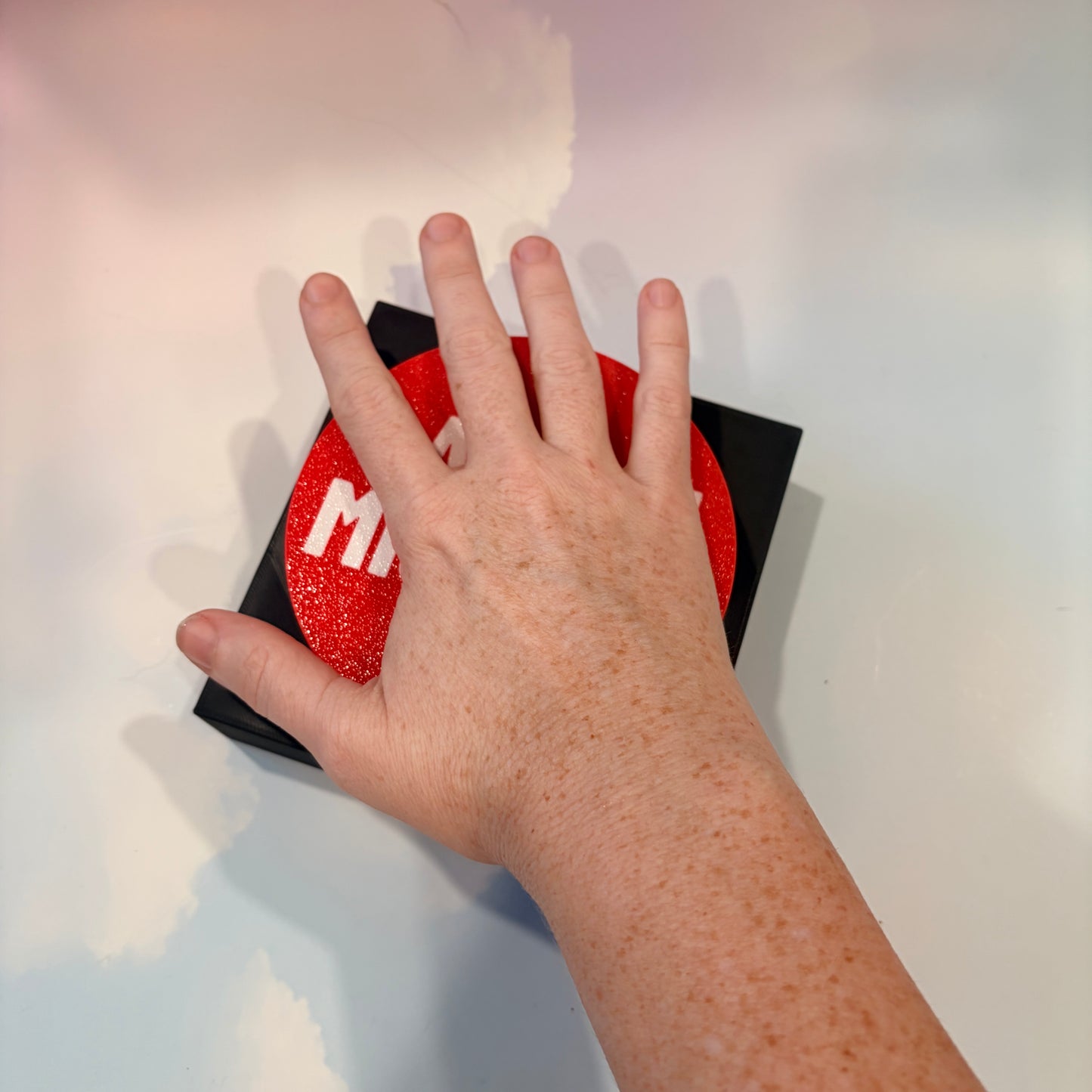 Oversized red 3D printed fidget button with white “LAUNCH MISSILES” lettering on a black square base, shown on a white surface.