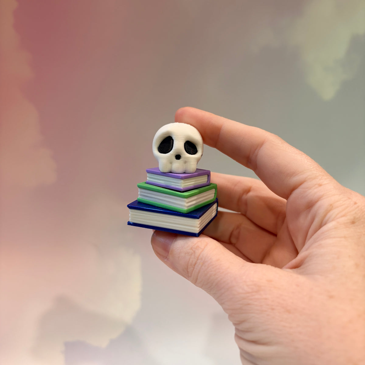3D printed skull fidget clicker on a colorful stack of books.