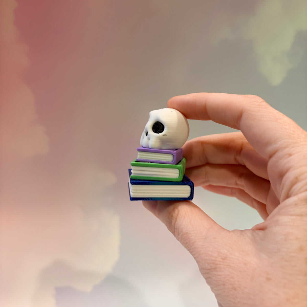 3D printed skull fidget clicker on a colorful stack of books.