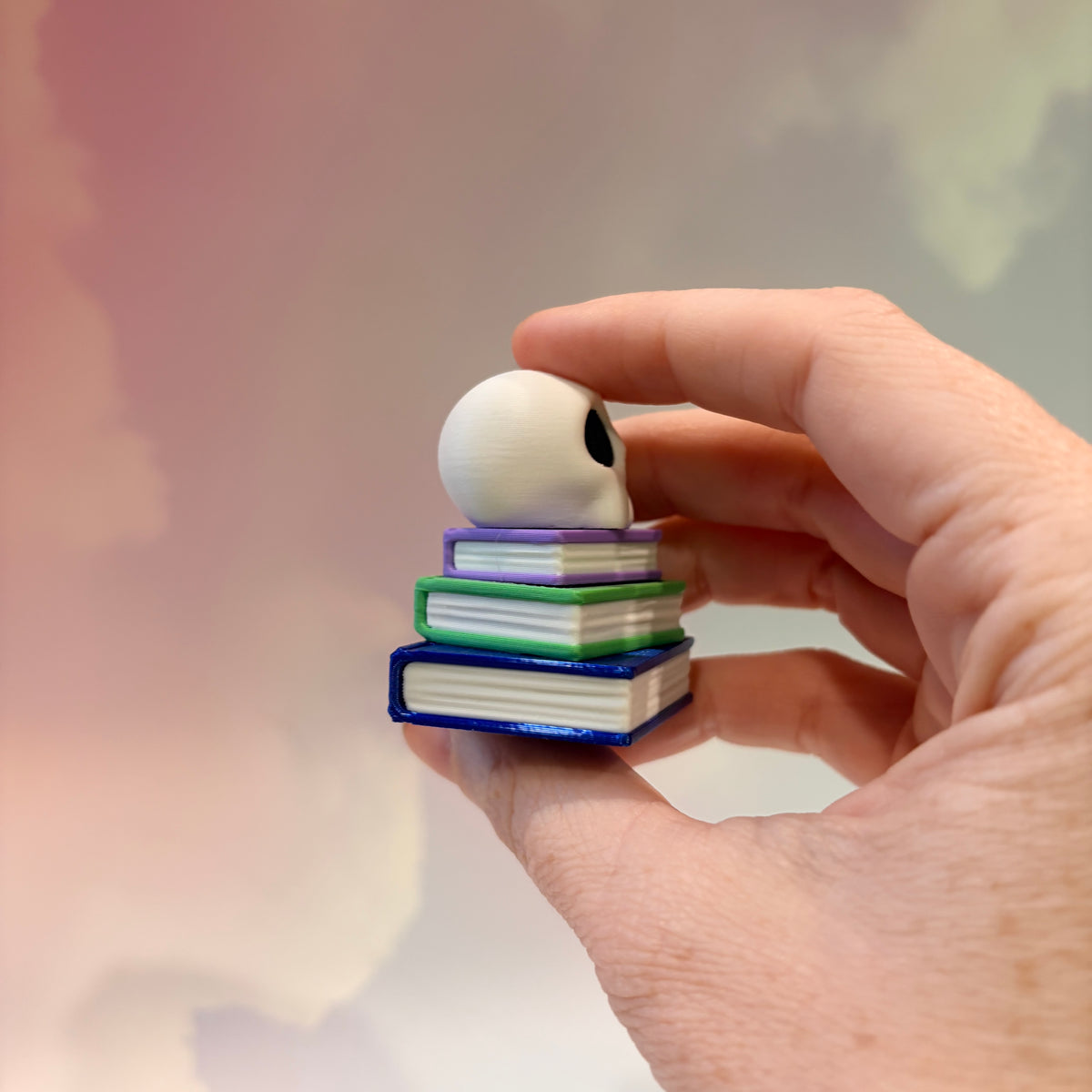 3D printed skull fidget clicker on a colorful stack of books.