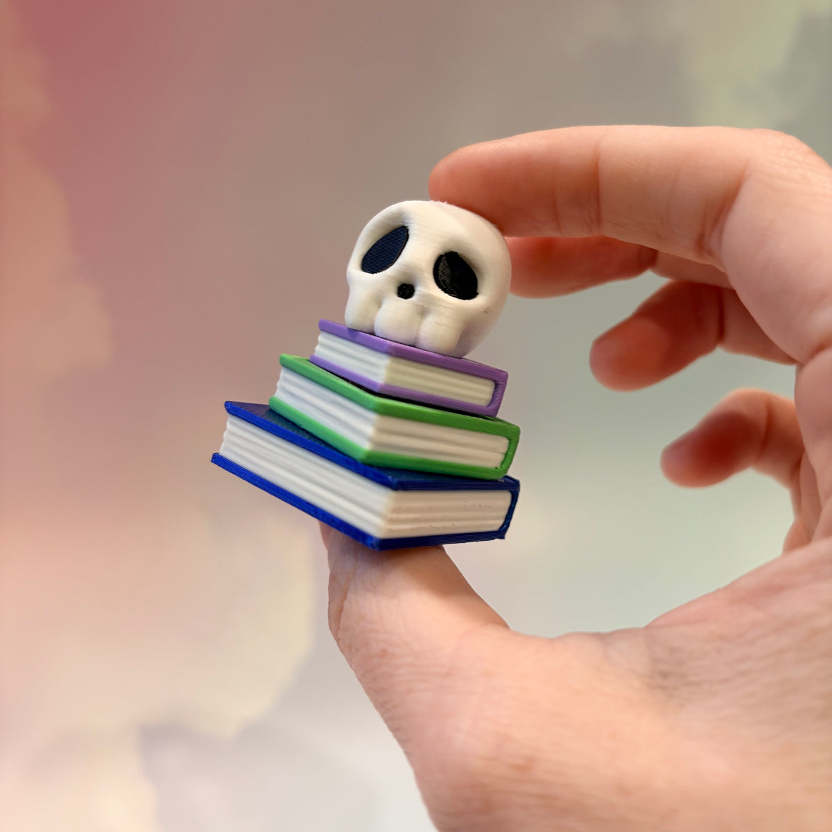 3D printed skull fidget clicker on a colorful stack of books.