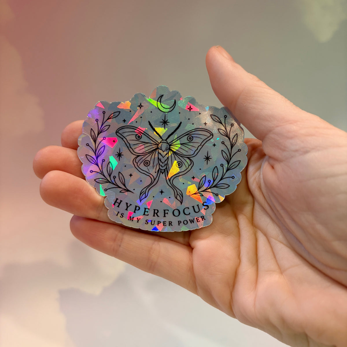 Holographic neurodivergent witchy sticker made from water-resistant vinyl, approximately 2.75 inches, featuring magical designs and neurodivergent humor.