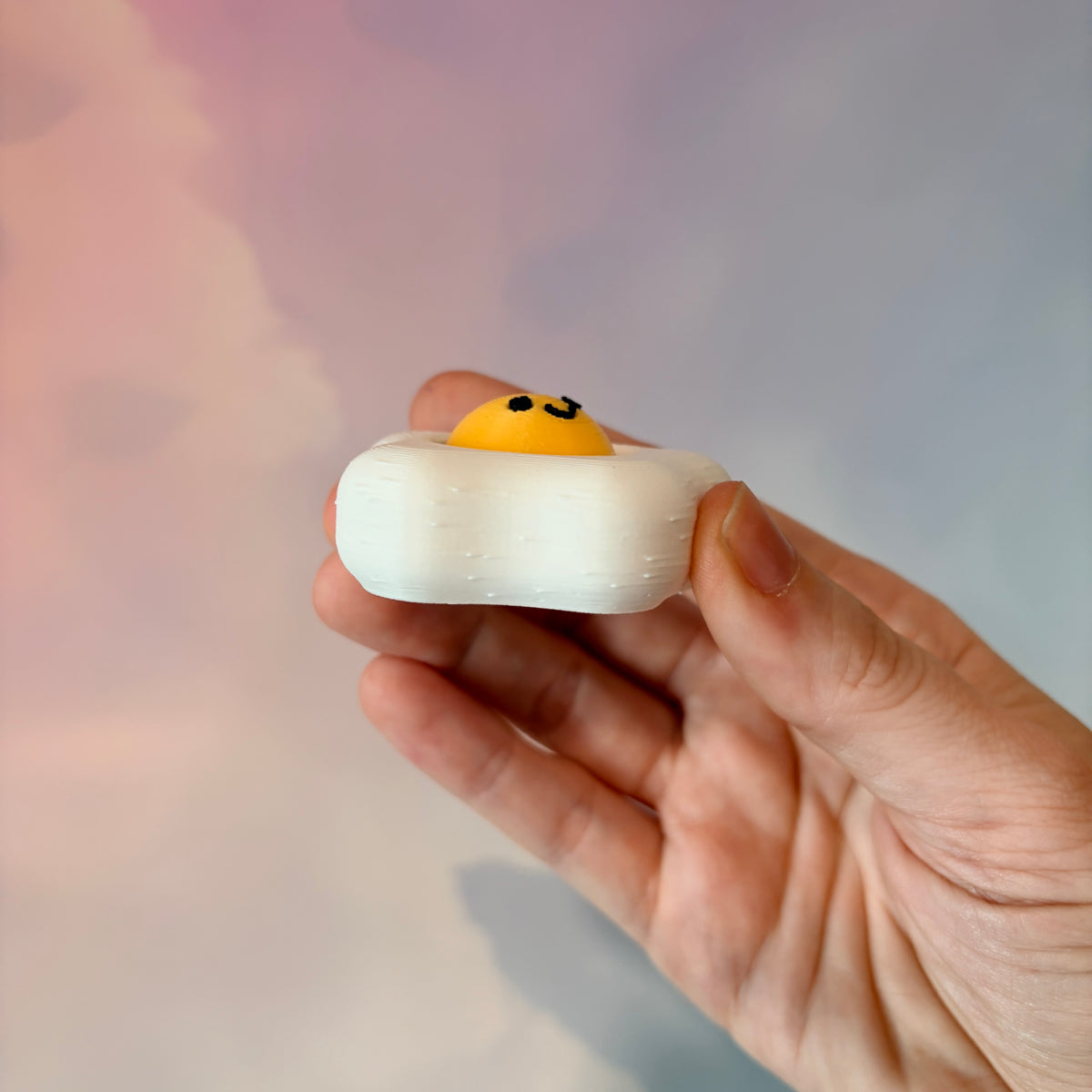 Fried egg shaped fidget clicker toy with a white egg and yellow yolk design, fun food themed desk accessory and satisfying fidget gift.