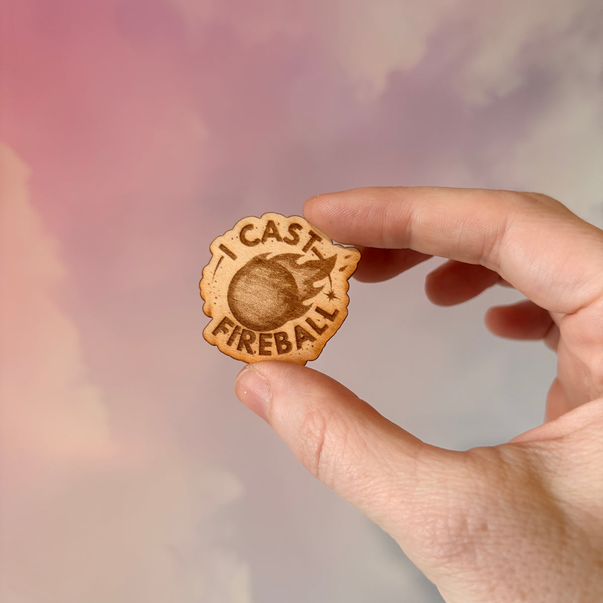 Laser engraved basswood pin reading "I Cast Fireball" for tabletop gamers.
