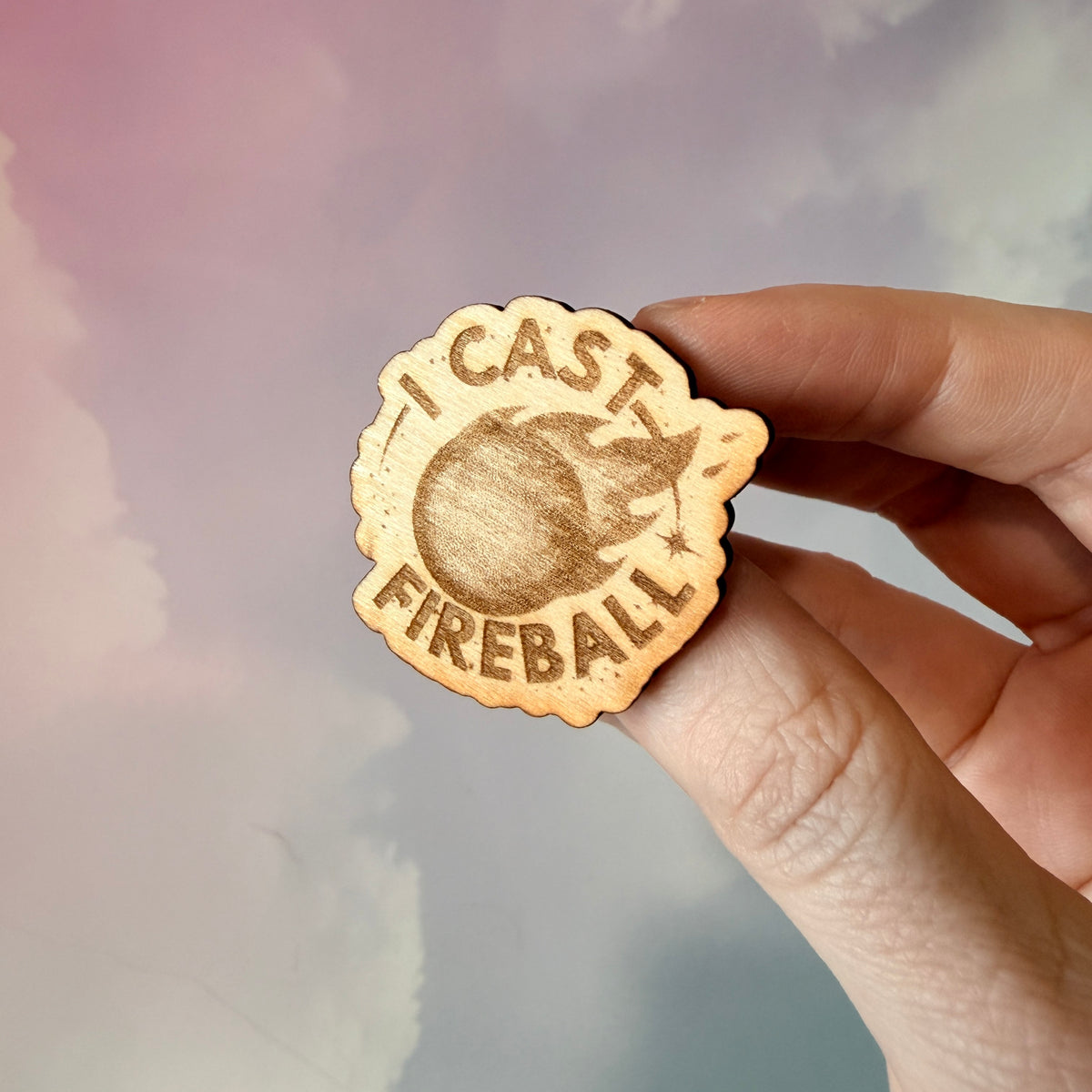 Laser engraved basswood pin reading "I Cast Fireball" for tabletop gamers.