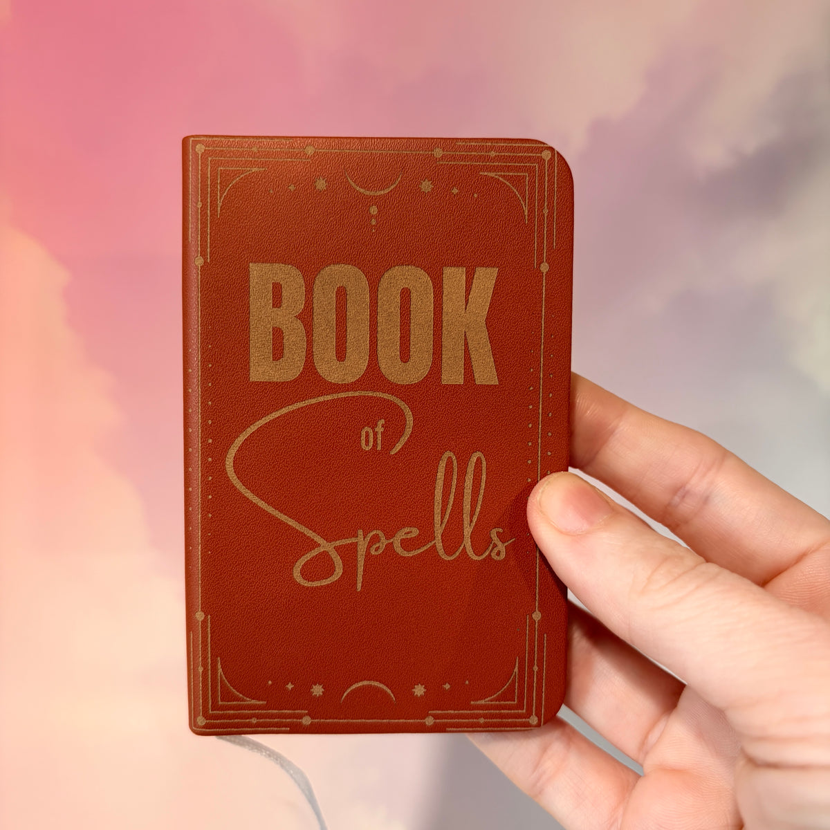 Mini green leather notebook with “Book of Spells” laser engraved on the cover in black lettering. Approximately 4 x 2.5 inches, with 50 lined pages. Available in brown, green, blue, gray, and black.
