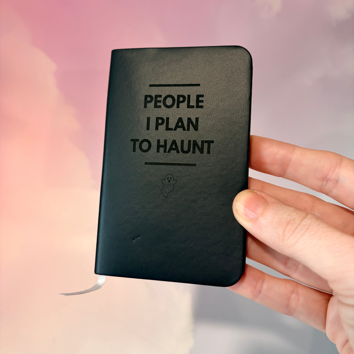 Mini blue notebook with “People I Plan to Haunt” laser engraved in black lettering and a tiny ghost illustration. Approximately 4 x 2.5 inches, with 50 lined pages. Available in brown, green, blue, gray, and black.
