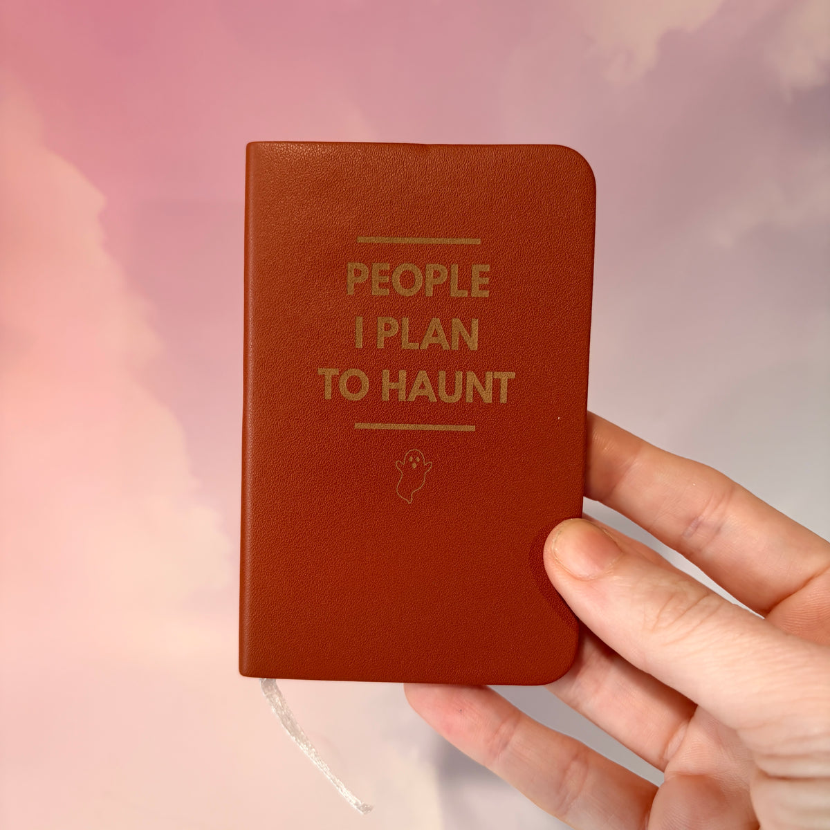 Mini blue notebook with “People I Plan to Haunt” laser engraved in black lettering and a tiny ghost illustration. Approximately 4 x 2.5 inches, with 50 lined pages. Available in brown, green, blue, gray, and black.
